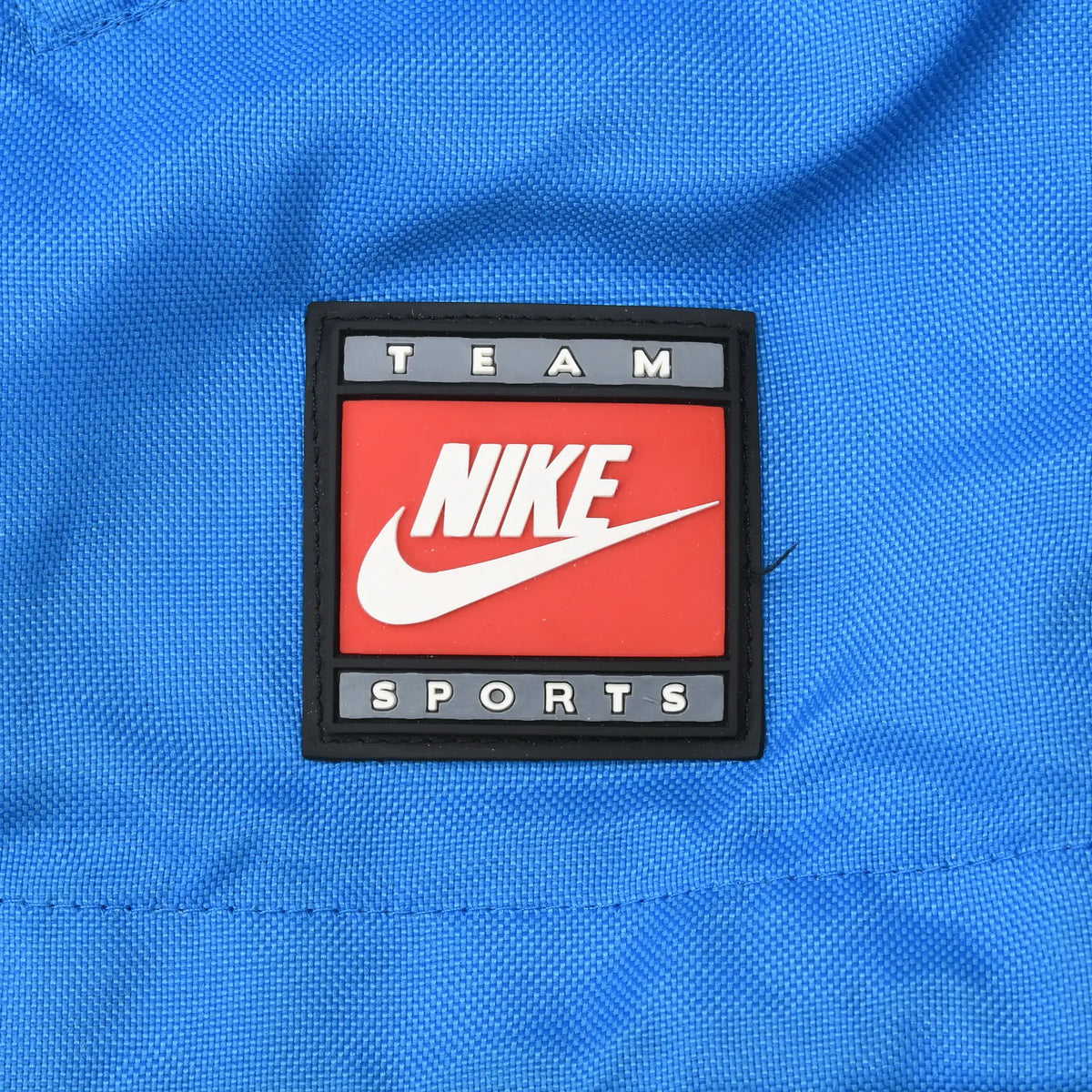 Close-up of red, white, and black Nike Team Sports patch on blue jacket
