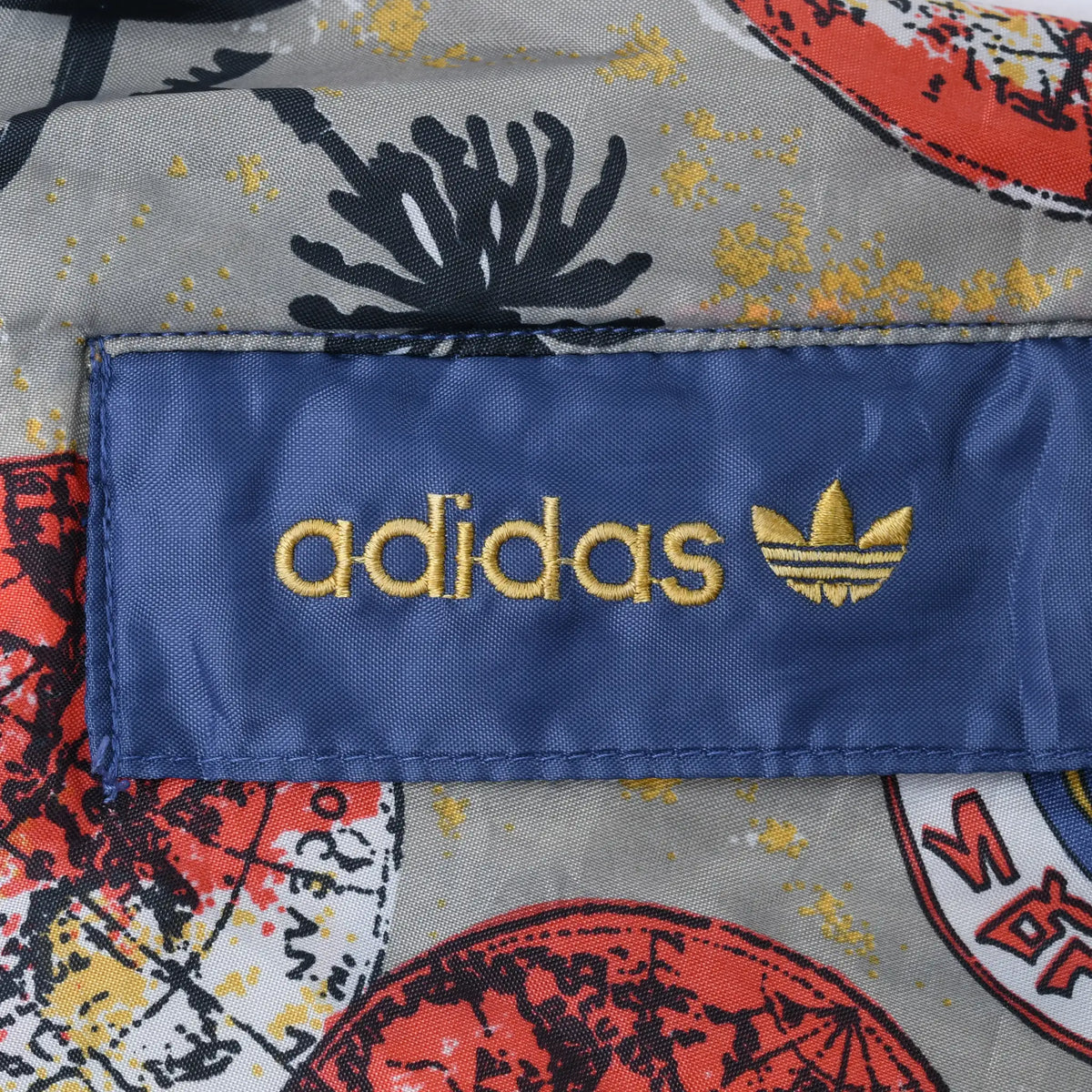 Gold Adidas wordmark and Trefoil embroidered on a blue patch over map-print fabric