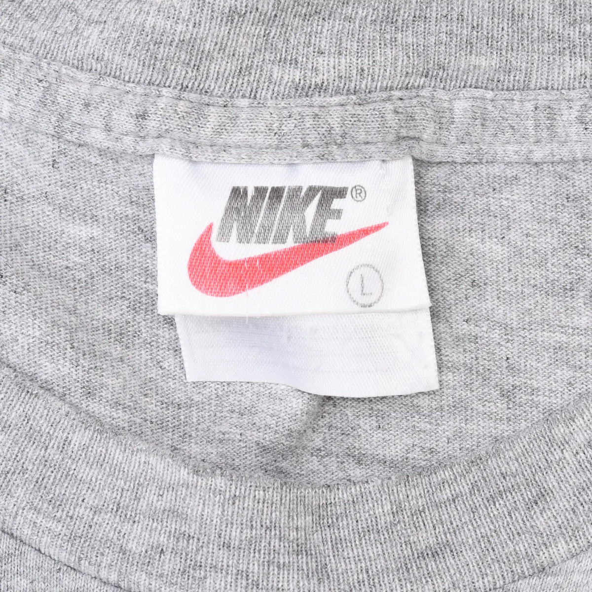 Close-up of Nike neck tag with black logo, red Swoosh, and L size mark