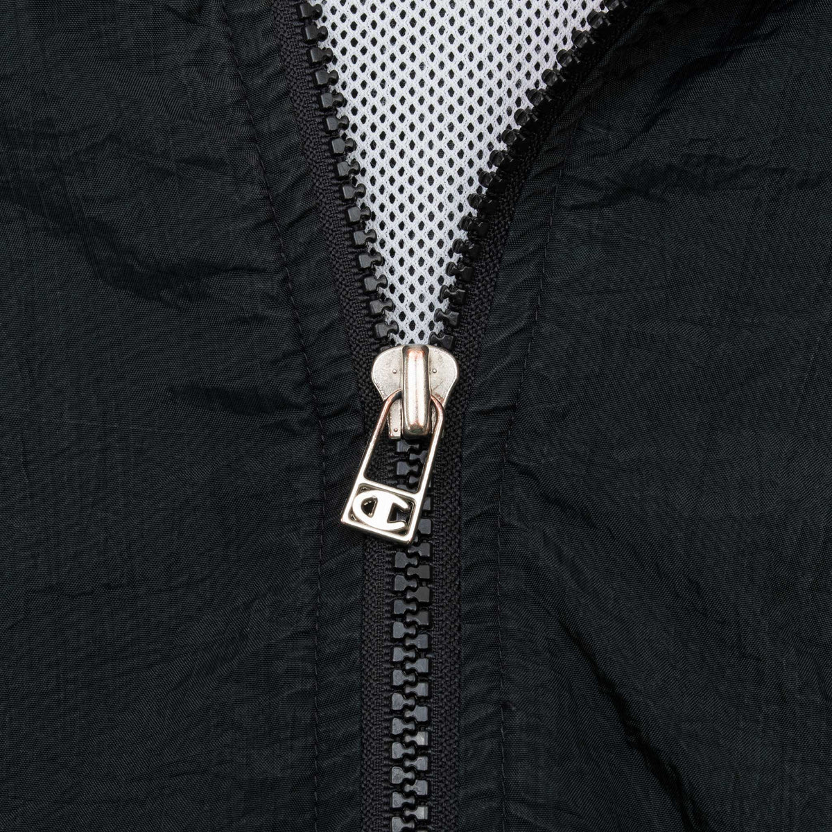 Close-up of Champion logo zipper pull on black windbreaker