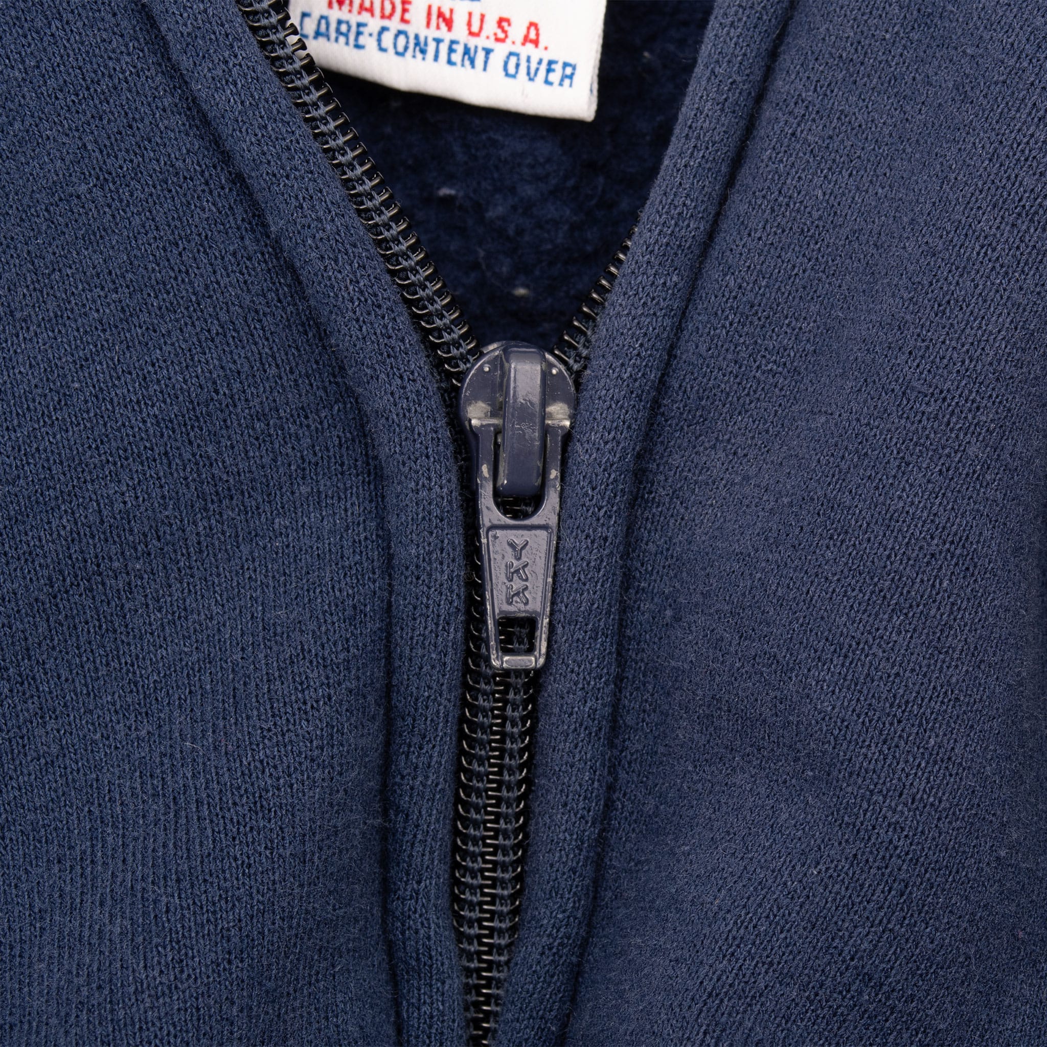 Close-up of YKK front zipper and navy sweatshirt fabric