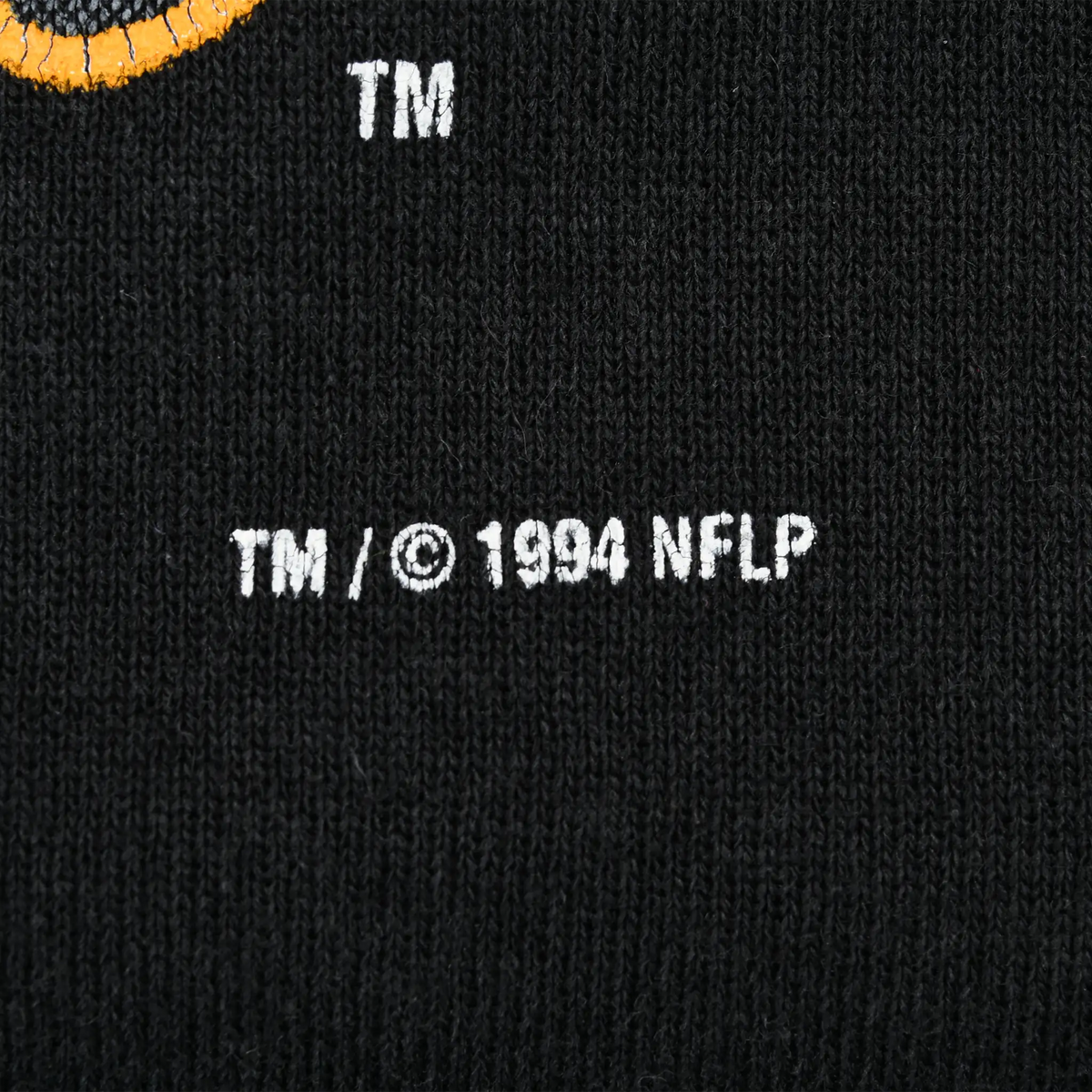 Close-up of white TM and 1994 NFLP copyright print on black sweatshirt fabric