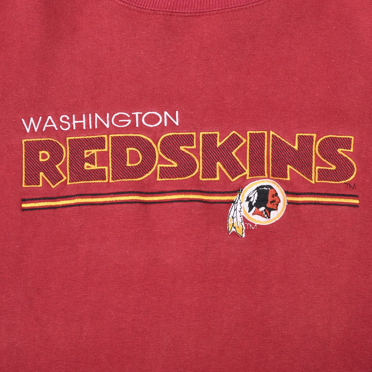 Close-up of embroidered Washington Redskins lettering, stripes, and team logo on burgundy fabric