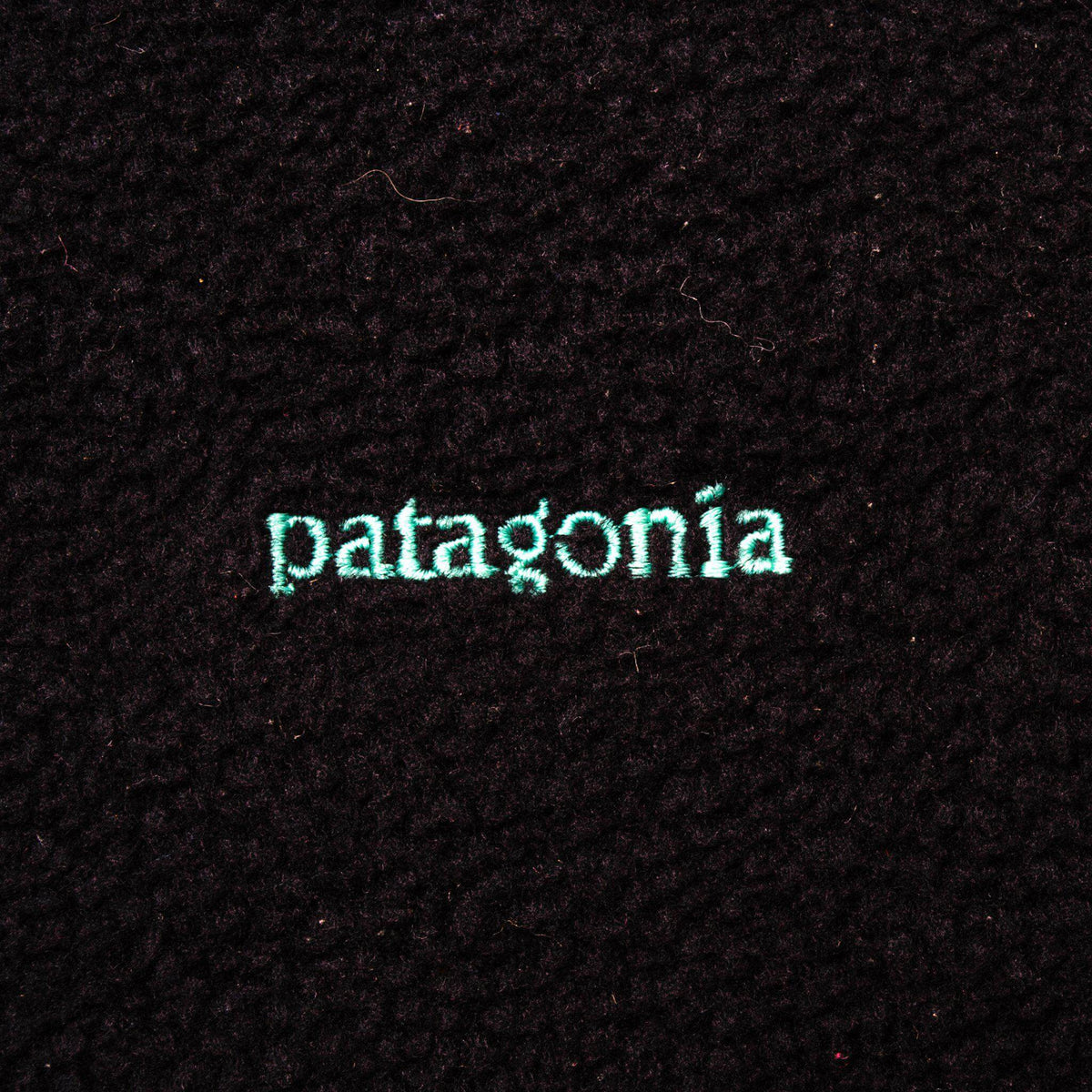 Teal Patagonia logo embroidery on black fabric