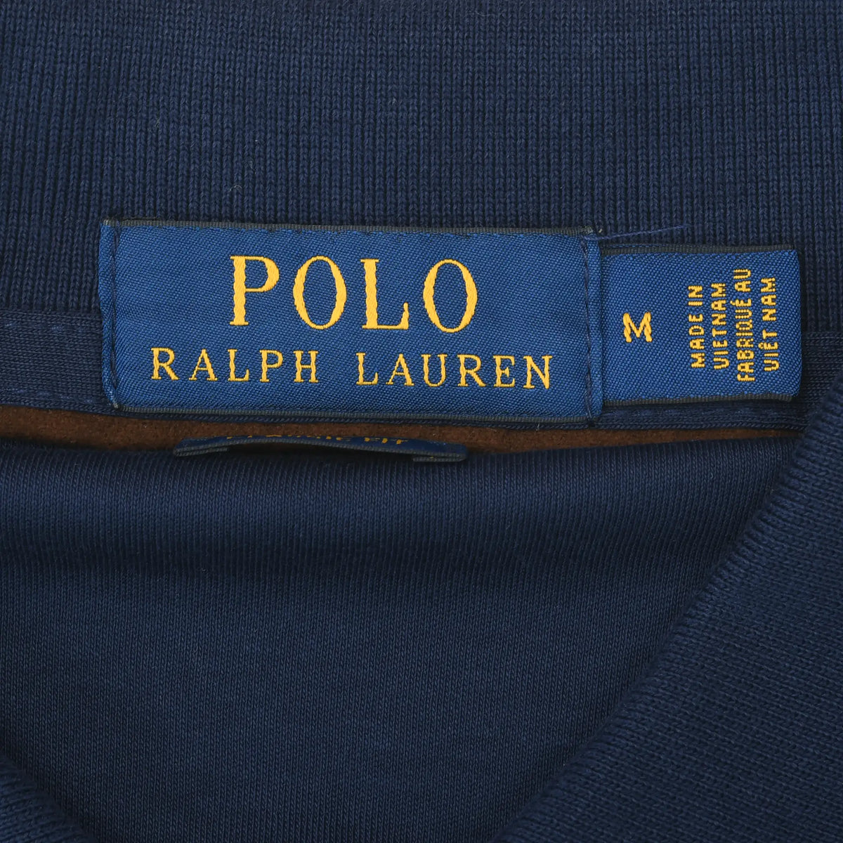 Close-up of Polo Ralph Lauren neck label marked size M on navy fabric