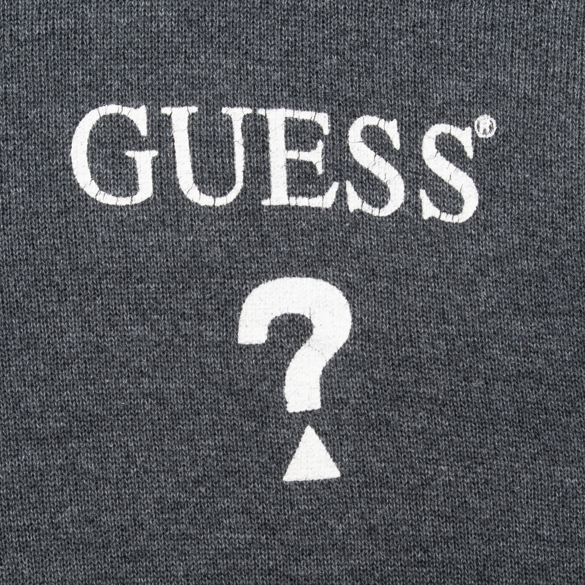 Close-up of white Guess logo and question mark chest print on grey fabric