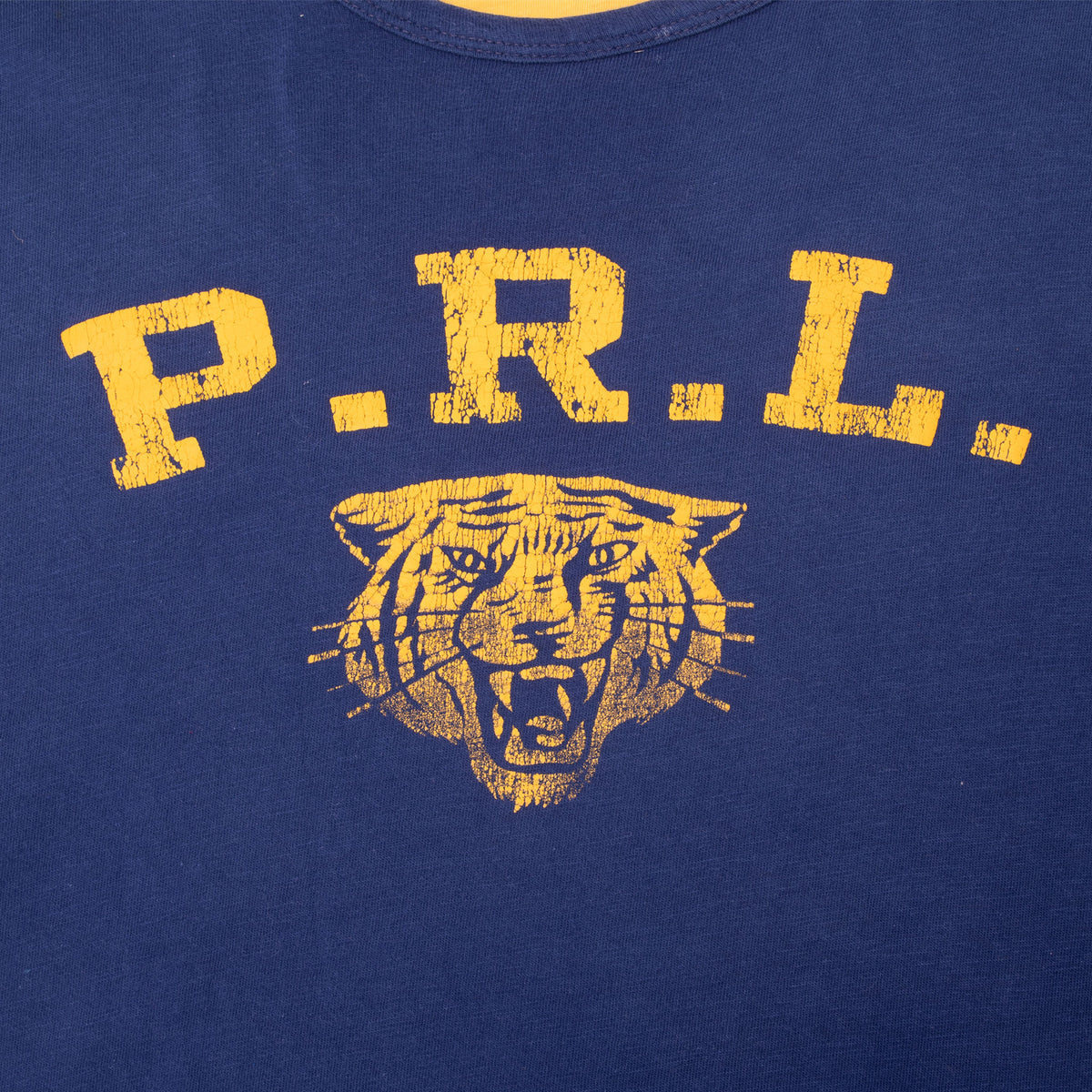Close-up of distressed yellow P.R.L. lettering and tiger print on navy T-shirt