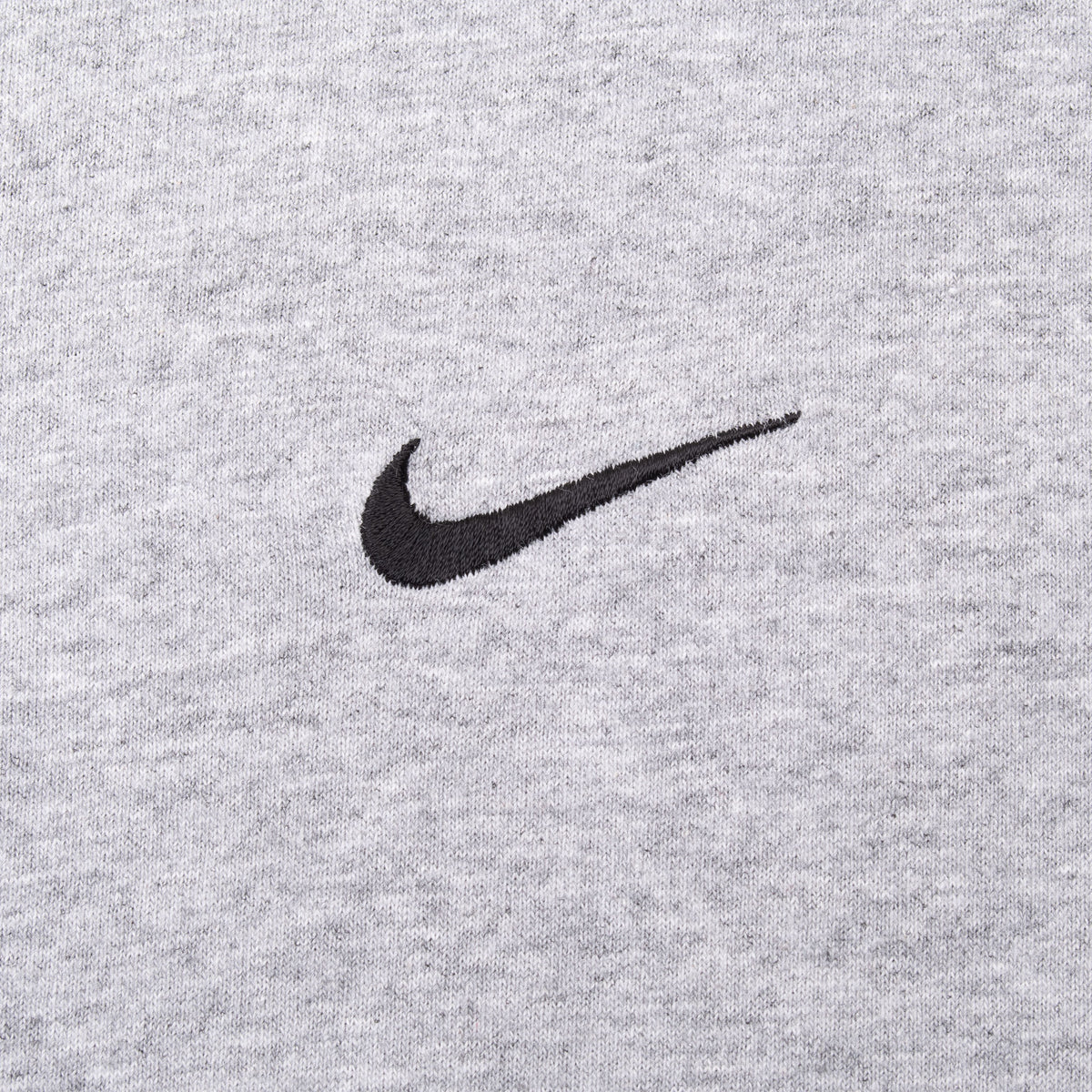 Close-up of small black Nike Swoosh embroidery on grey T-shirt