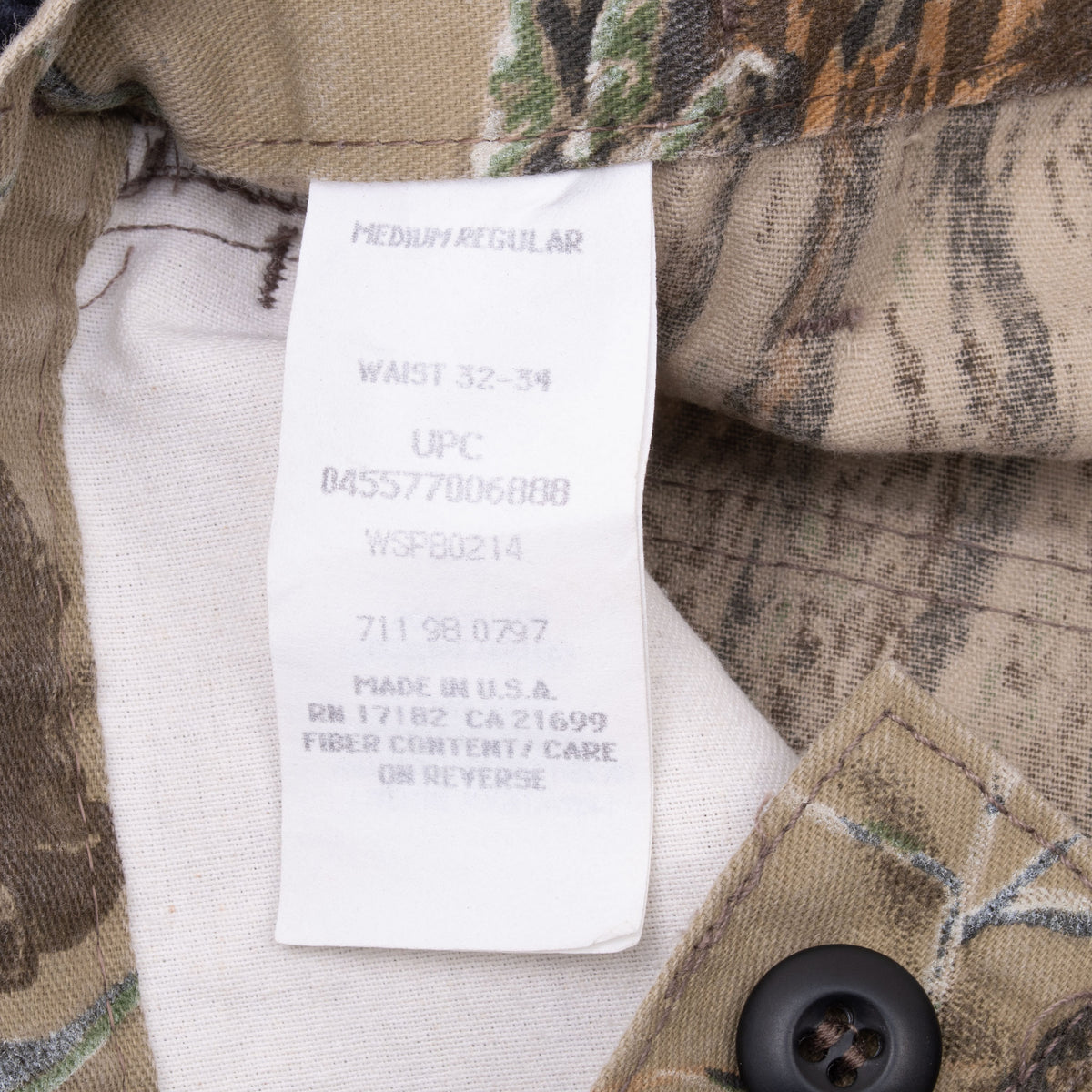 Interior tag on Realtree camouflage pants showing medium regular, waist 32–34, and made in USA