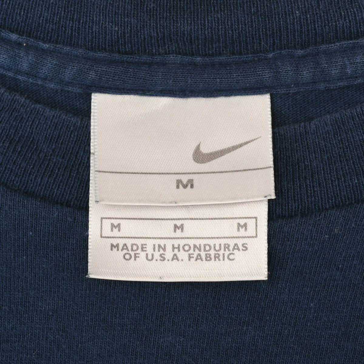 Close-up of Nike neck tag marked size M and Made in Honduras of U.S.A. fabric