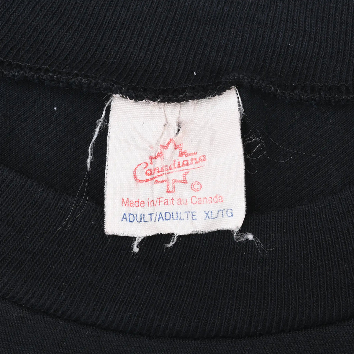 Neck tag on black T-shirt showing Canadiana, Made in Canada, and adult XL markings