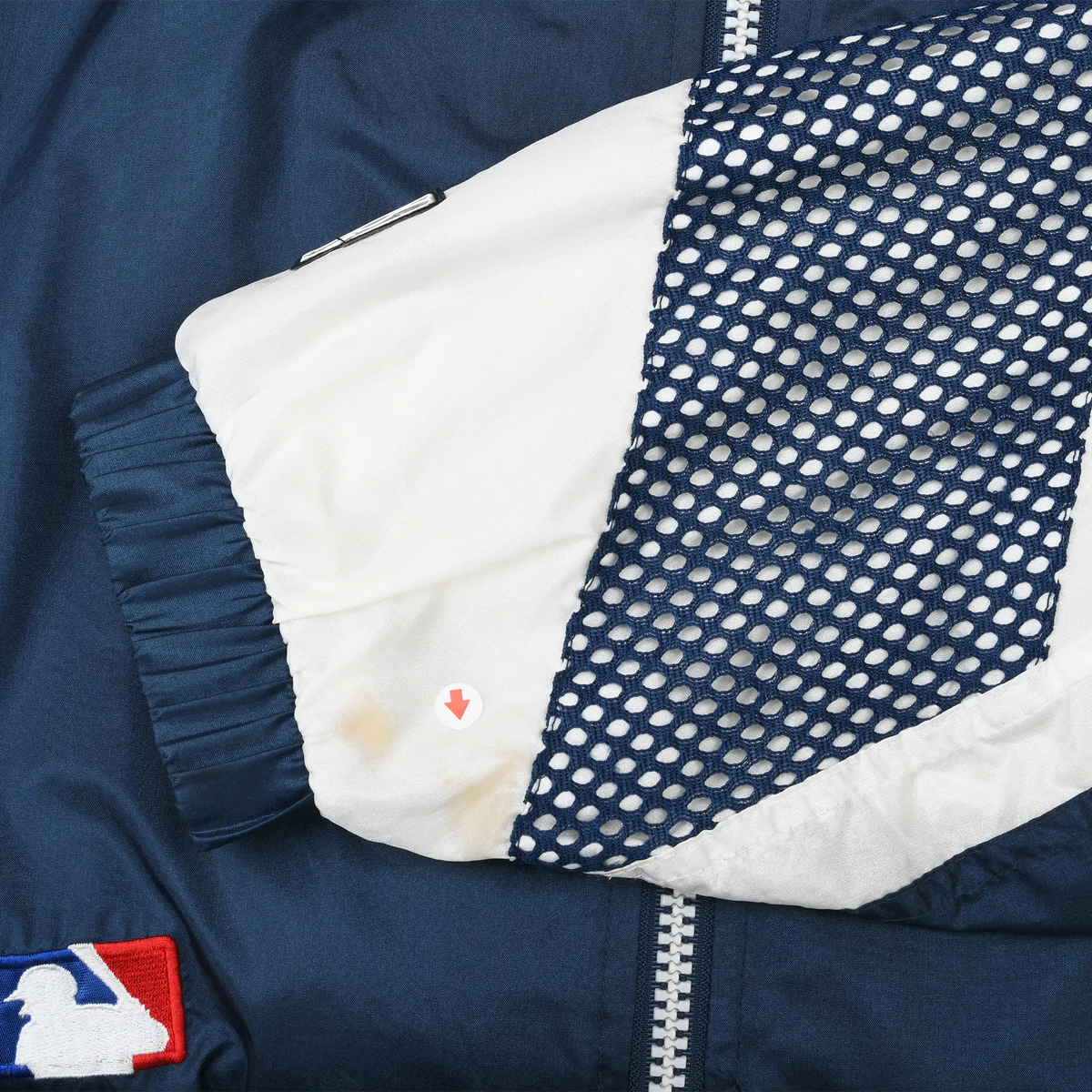 Close-up of white and navy mesh sleeve panel with small yellow discoloration near the cuff