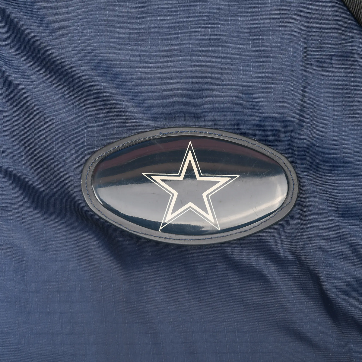 Close-up of oval Dallas Cowboys star logo patch on navy jacket fabric
