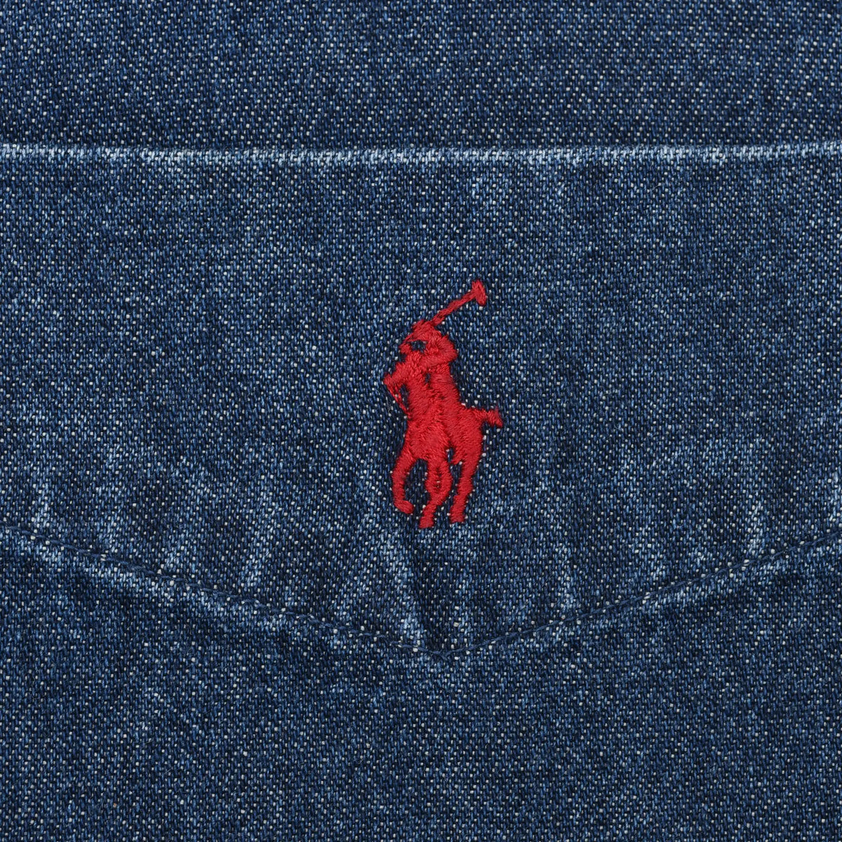Close-up of red Polo Ralph Lauren pony embroidery on dark blue denim chest pocket