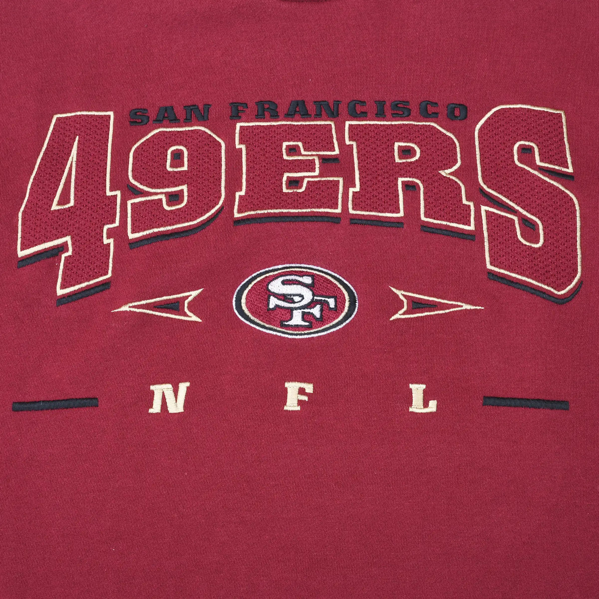 Close-up of embroidered San Francisco 49ers chest lettering, team logo, and NFL initials