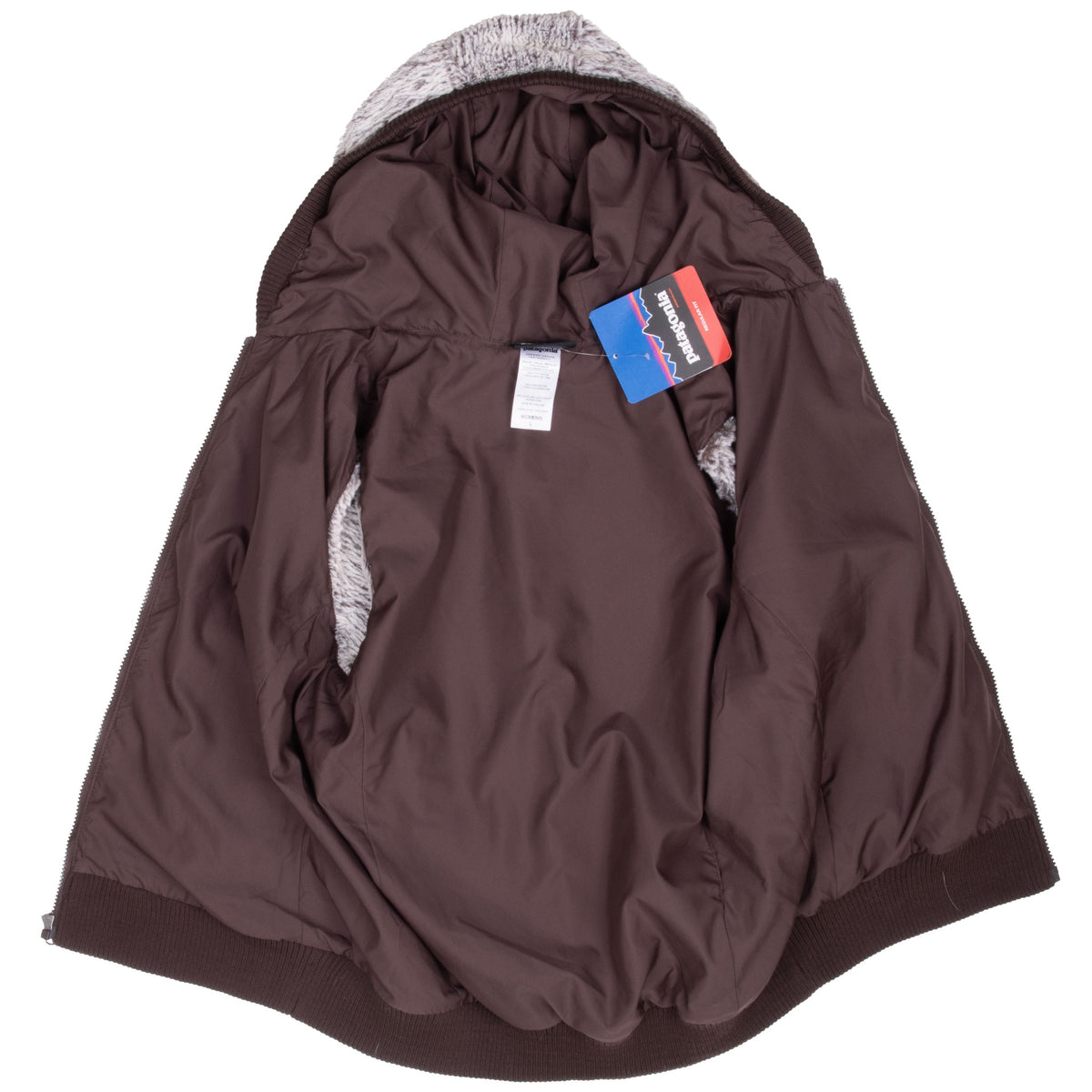 Open Patagonia Canejo vest showing brown interior lining, hood, labels, and hangtag
