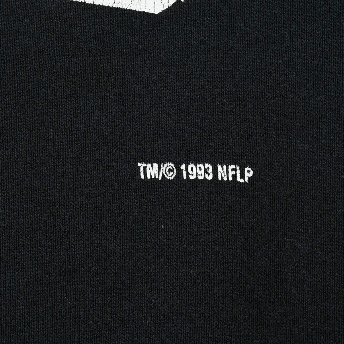 Close-up of 1993 NFLP trademark text printed on black fabric