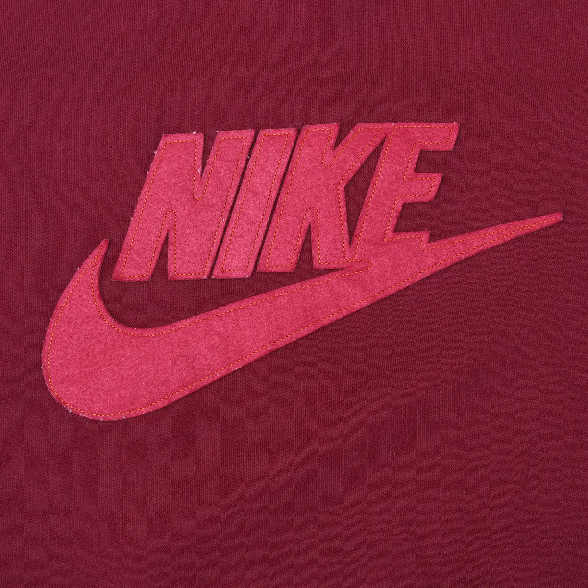 Close-up of red Nike spellout and Swoosh applique on burgundy sweatshirt
