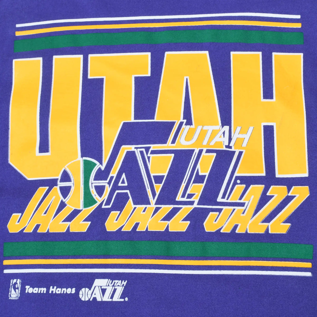 Close-up of yellow, green and white Utah Jazz front graphic on purple fabric