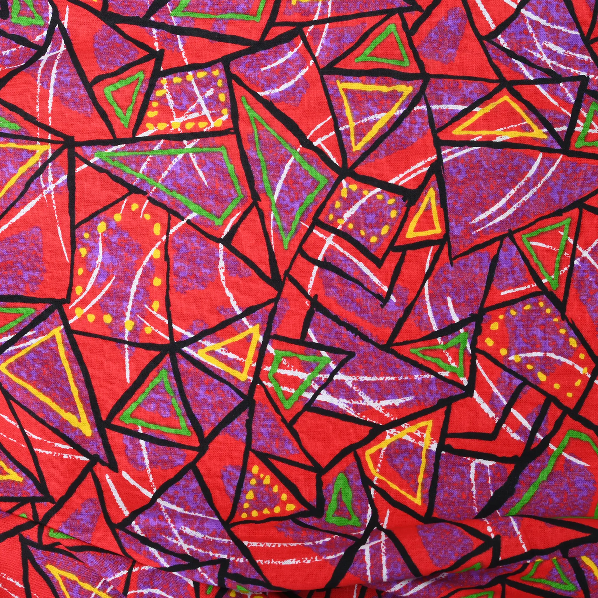 Close-up of red fabric with purple, green and yellow geometric all-over print