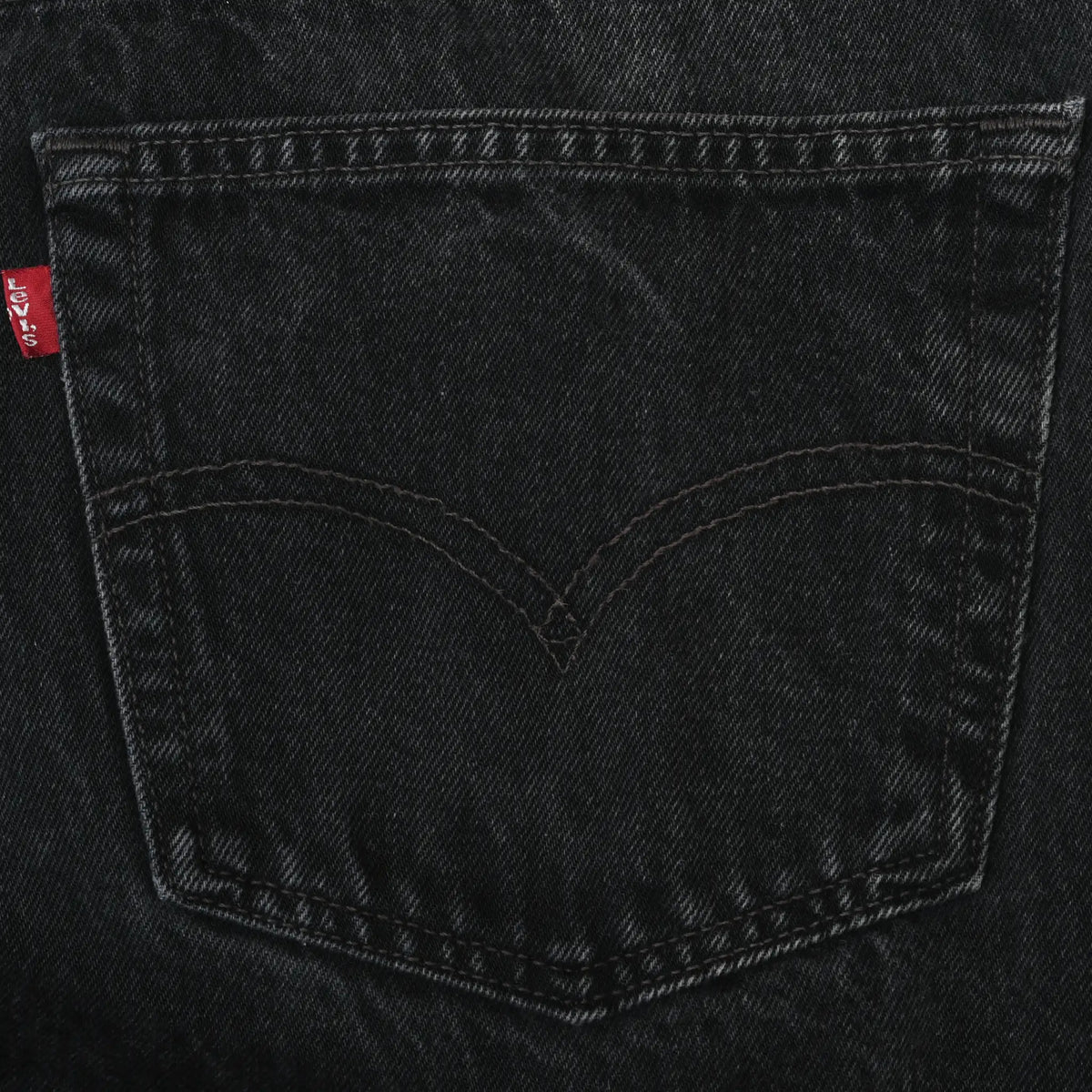 Close-up of Levi's black denim back pocket with arcuate stitching and red tab