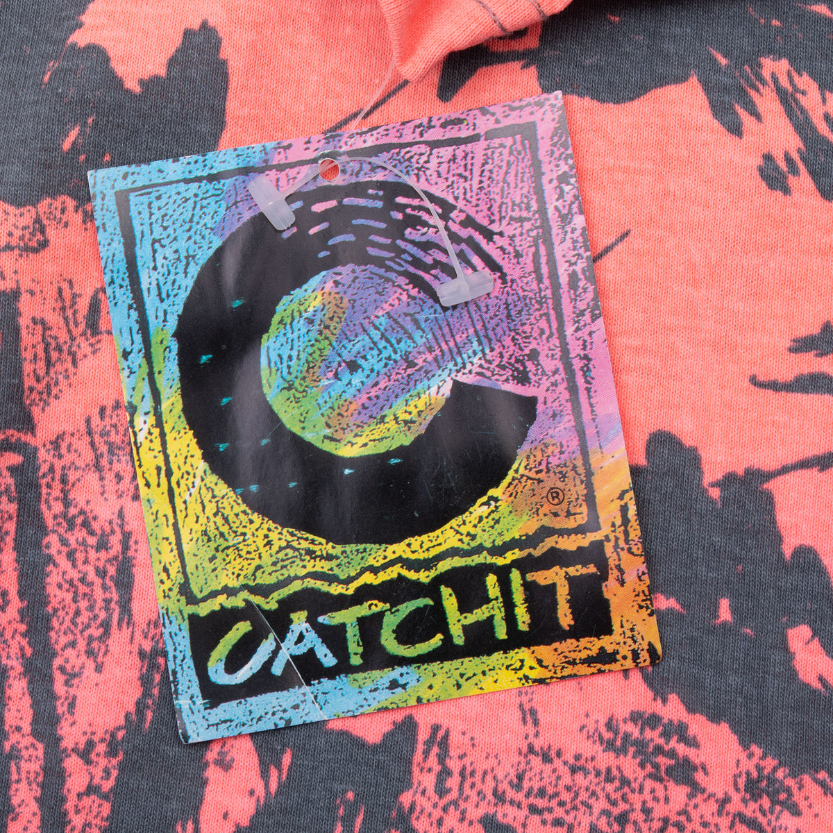 Colorful Catchit hangtag attached to pink and charcoal printed fabric