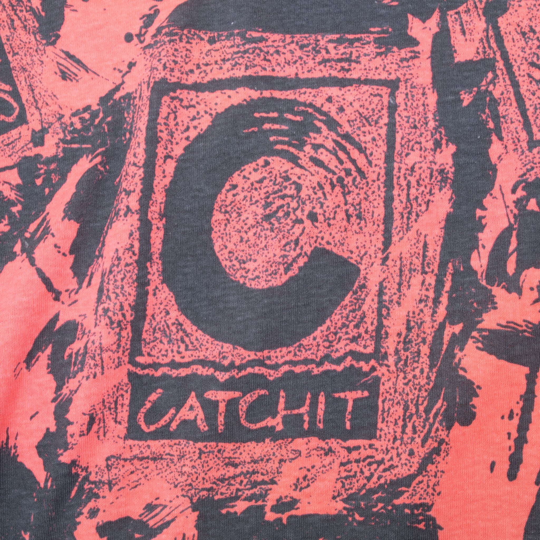 Close-up of Catchit logo graphic on pink and charcoal T-shirt