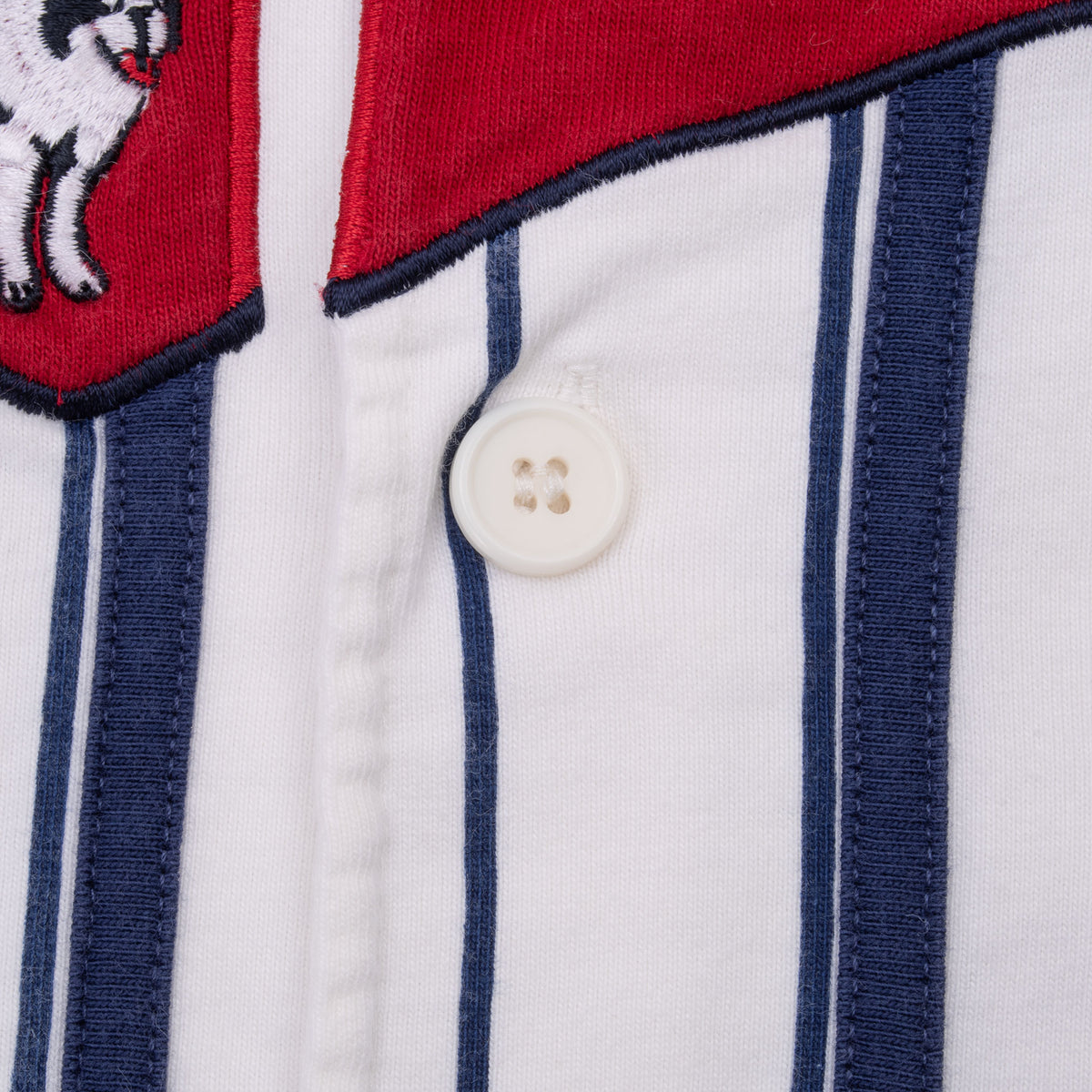 Close-up of jersey button, navy trim, and red embroidered logo edge