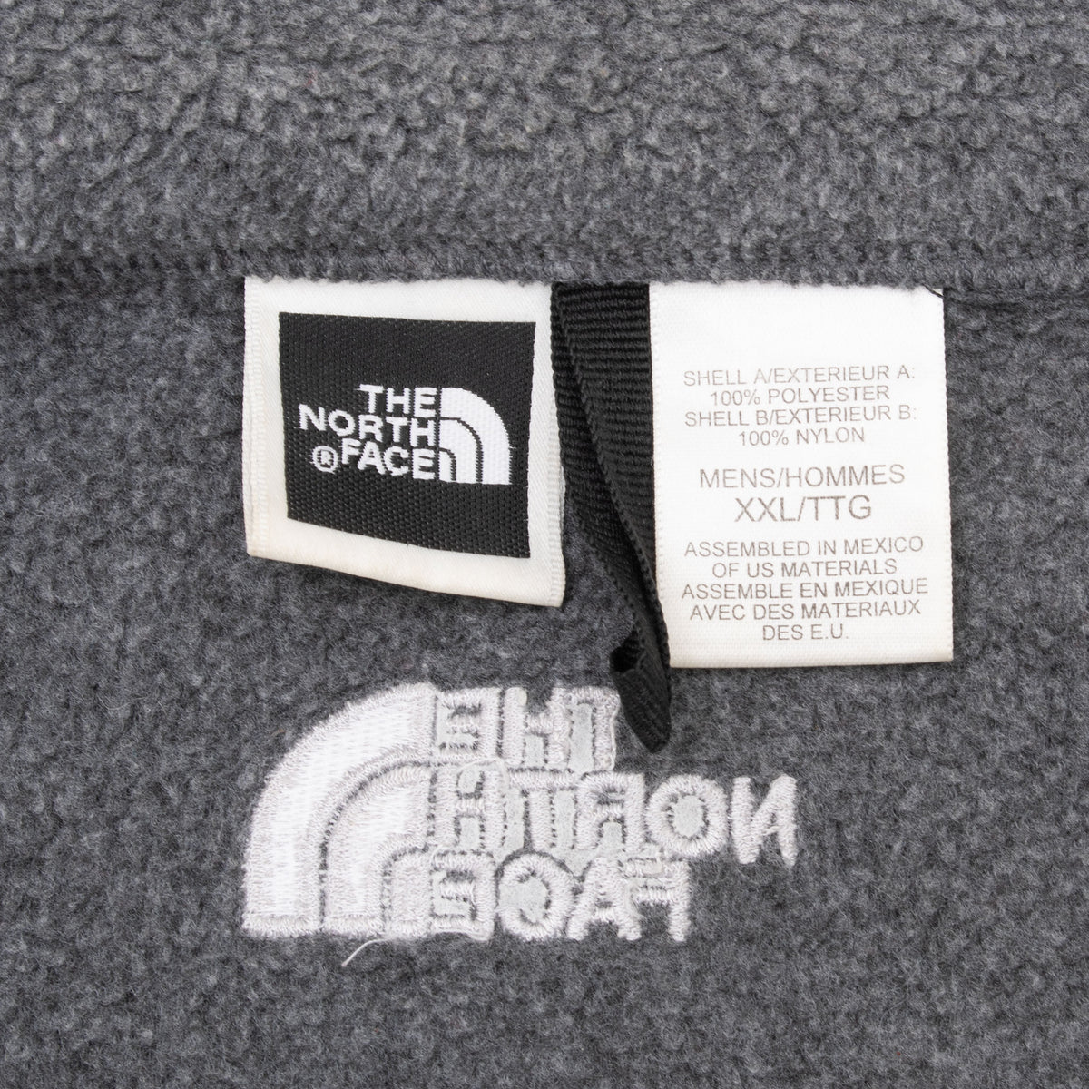 The North Face neck and size tags inside grey fleece jacket, marked men's XXL