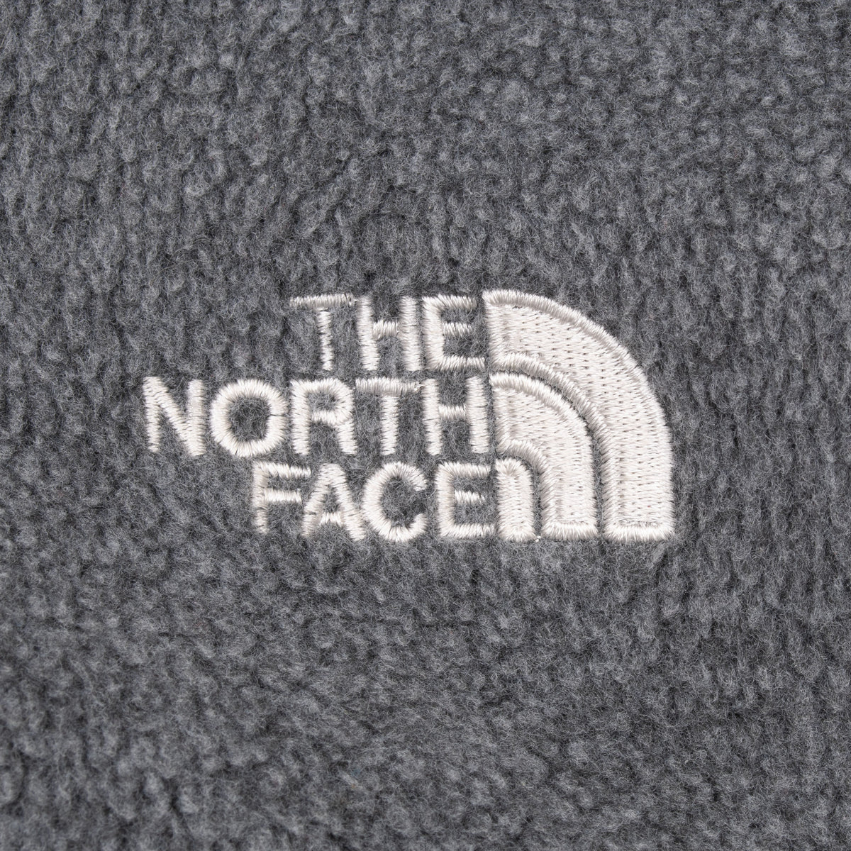 Close-up of white The North Face logo embroidery on grey fleece