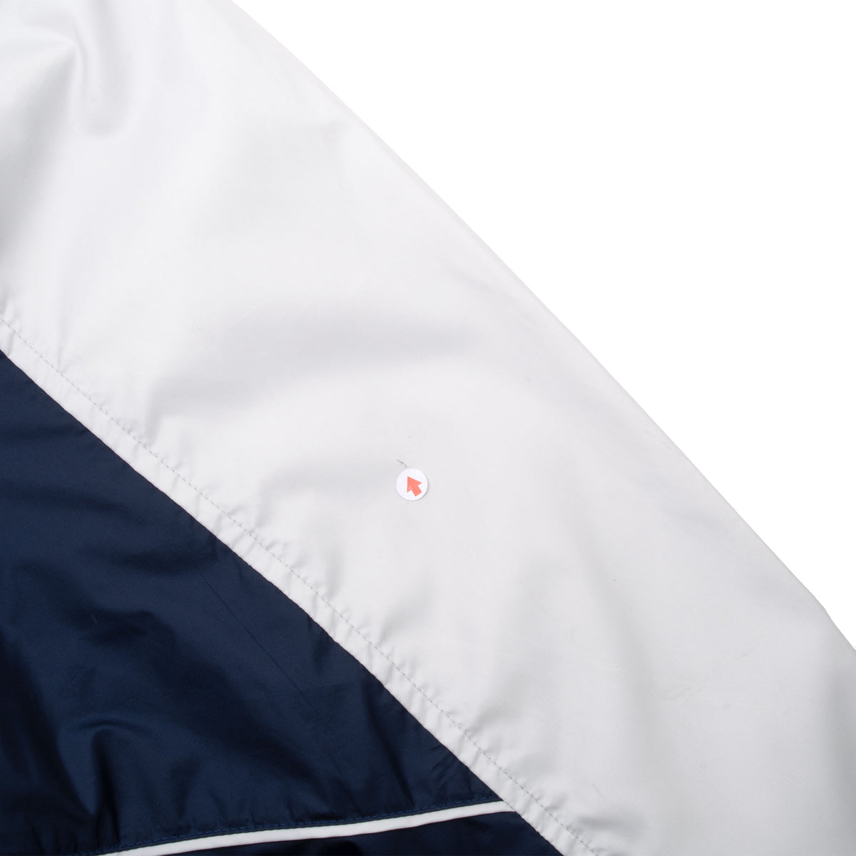 Close-up of small blemish on white sleeve beside the navy panel and piping