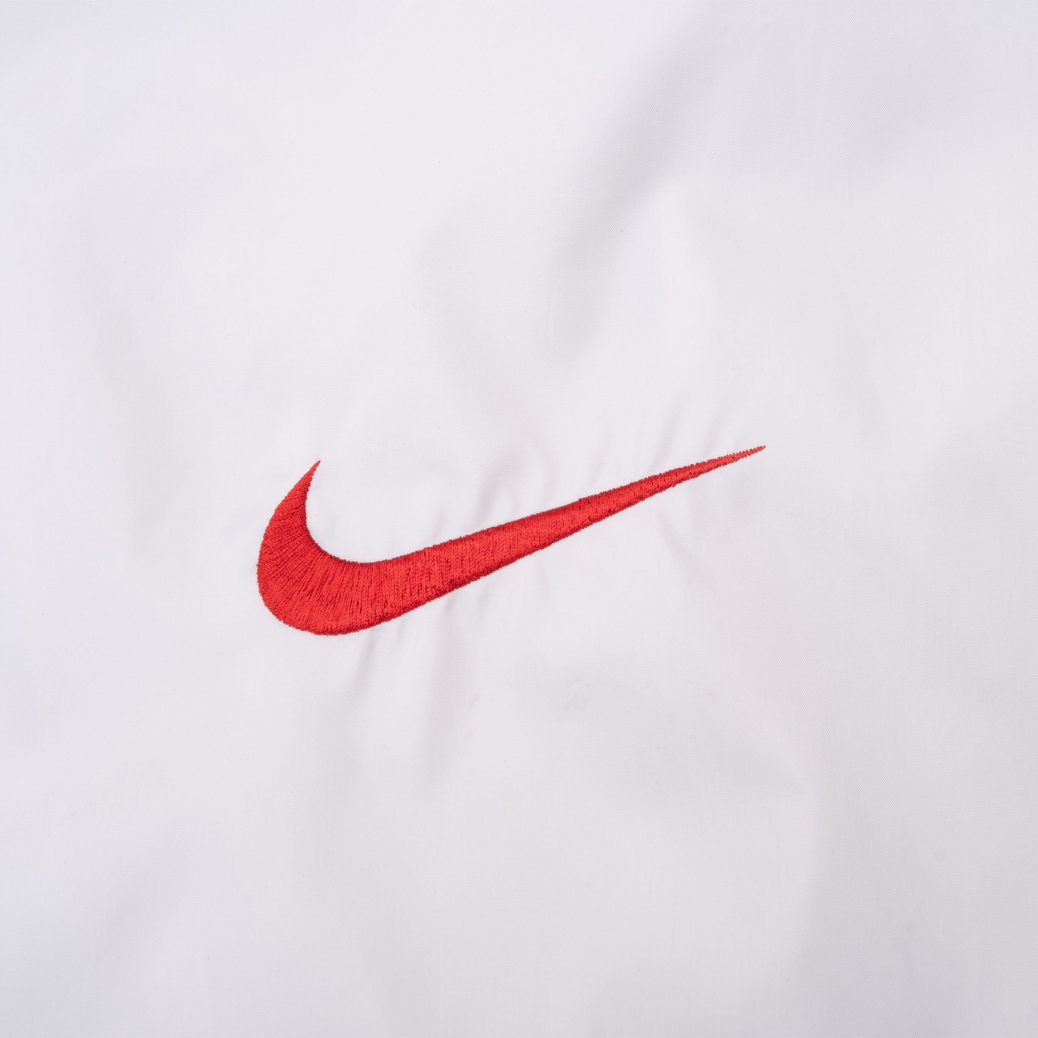 Close-up of oversized red embroidered Nike Swoosh on white back fabric
