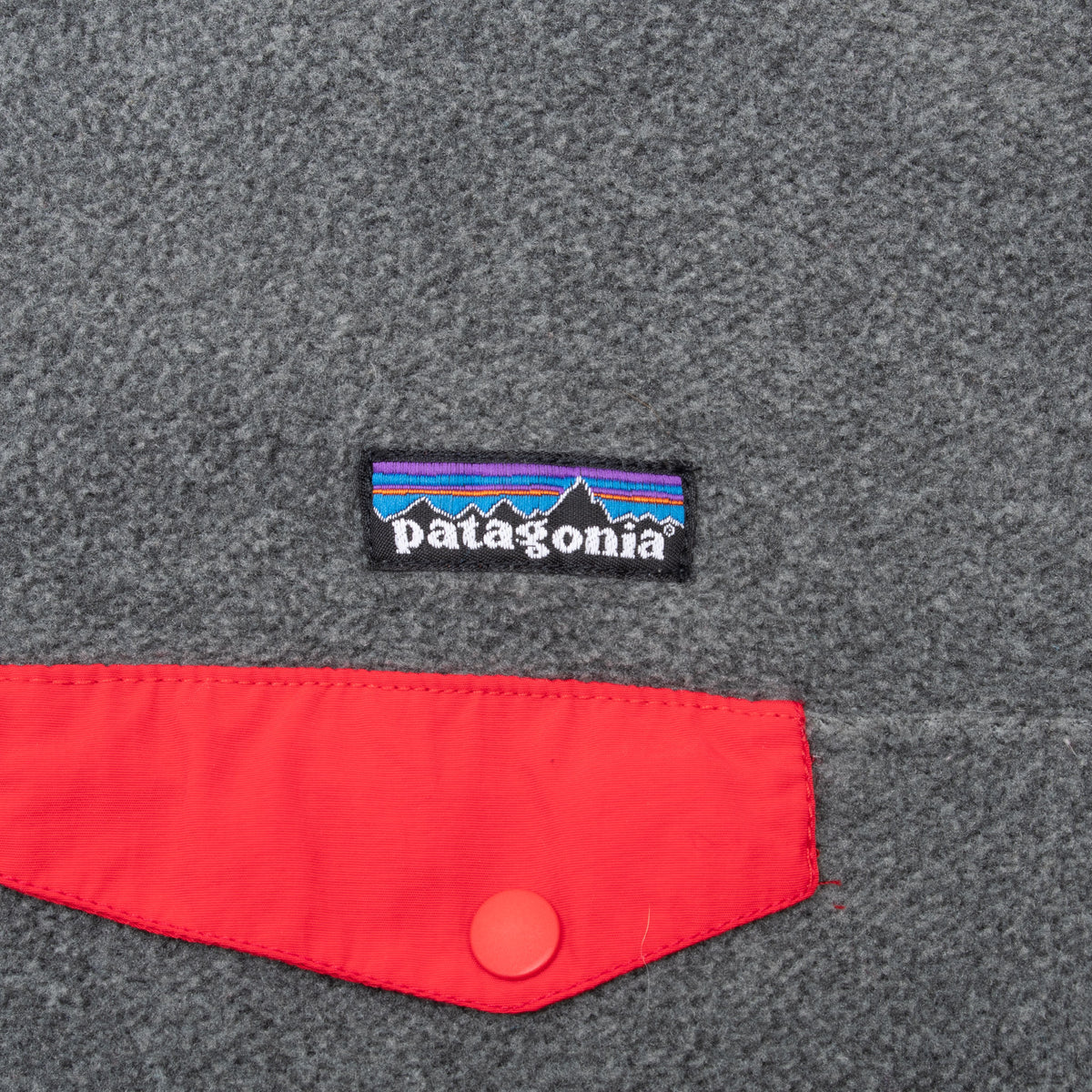 Patagonia logo and red snap chest pocket detail on grey Synchilla fleece
