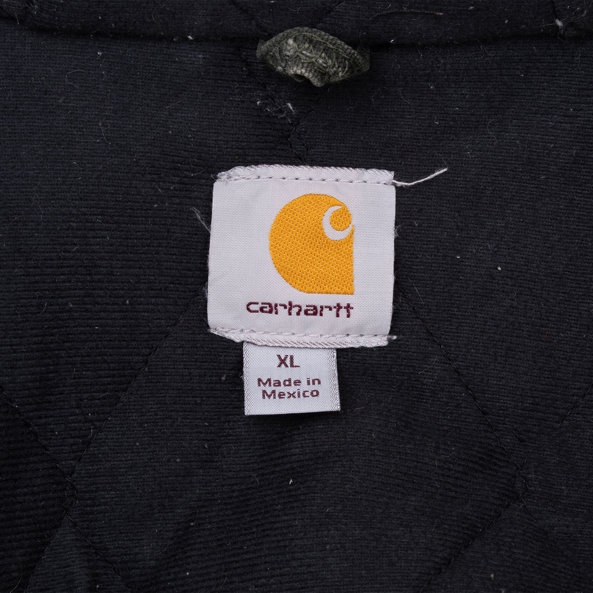 Carhartt neck logo and XL size tag inside the black quilted jacket lining