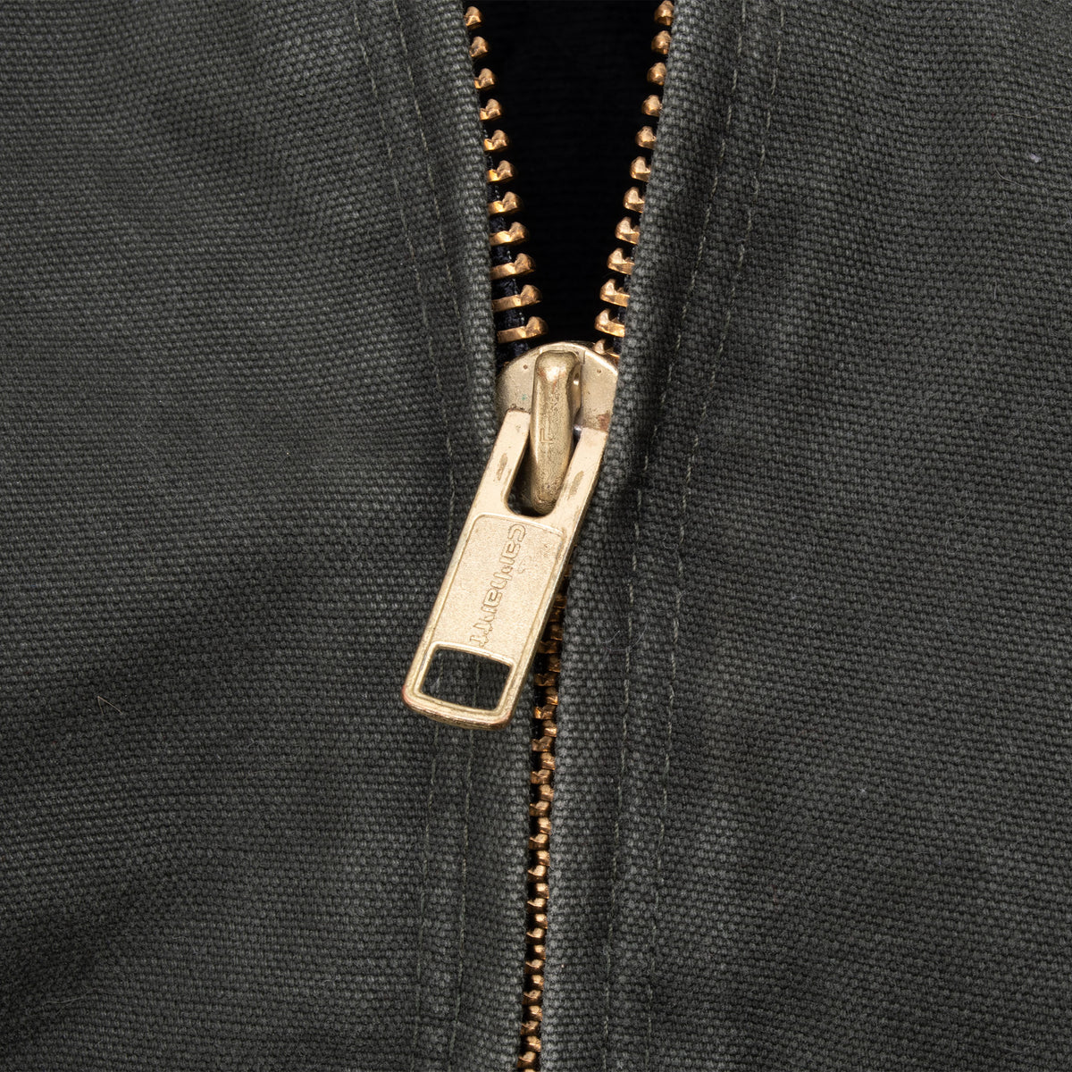 Close-up of metal front zipper on moss green Carhartt jacket