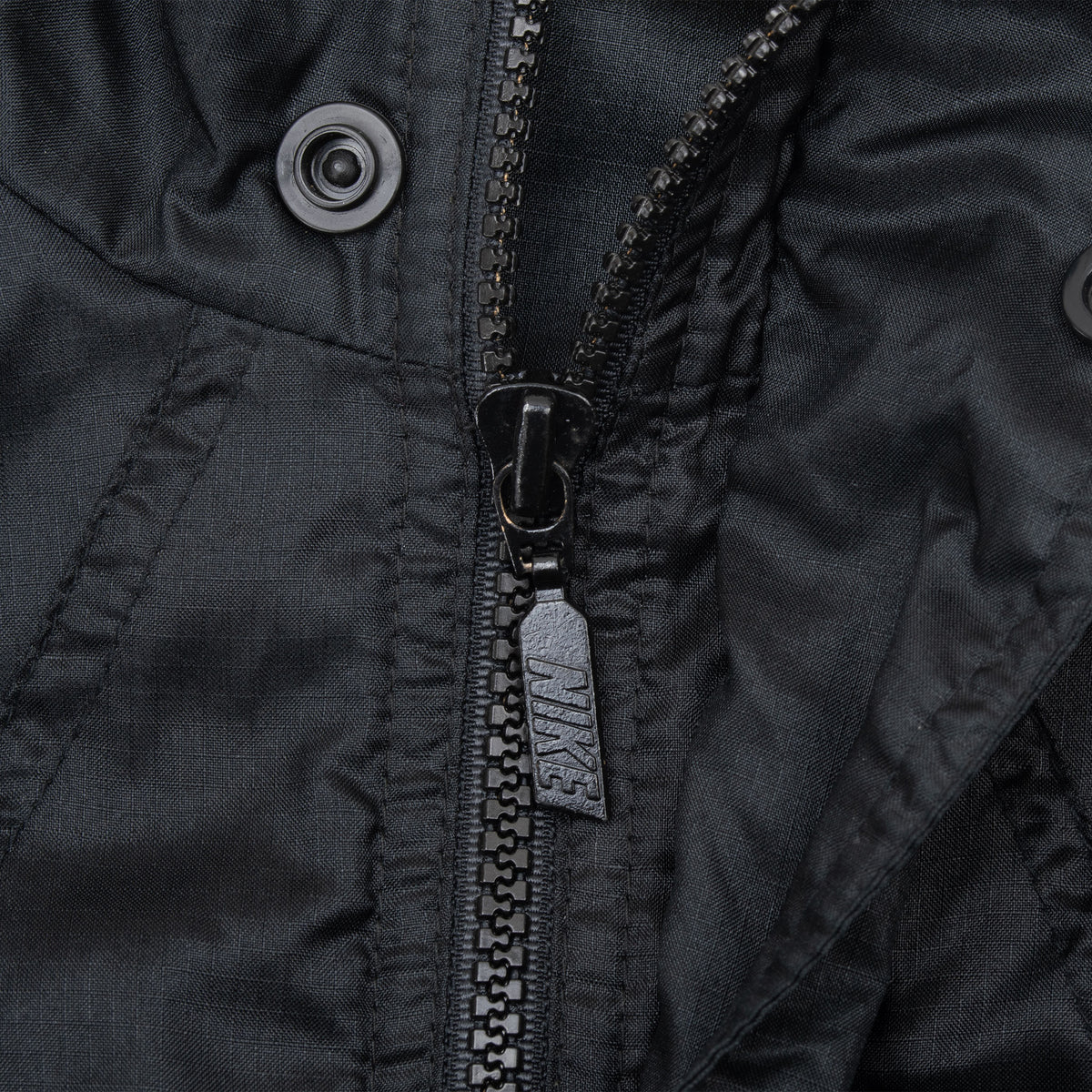 Close-up of black windbreaker zipper and snap-button placket