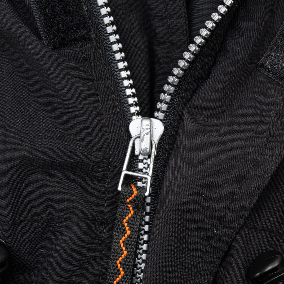 Close-up of front zipper, snap placket and orange accent stitching