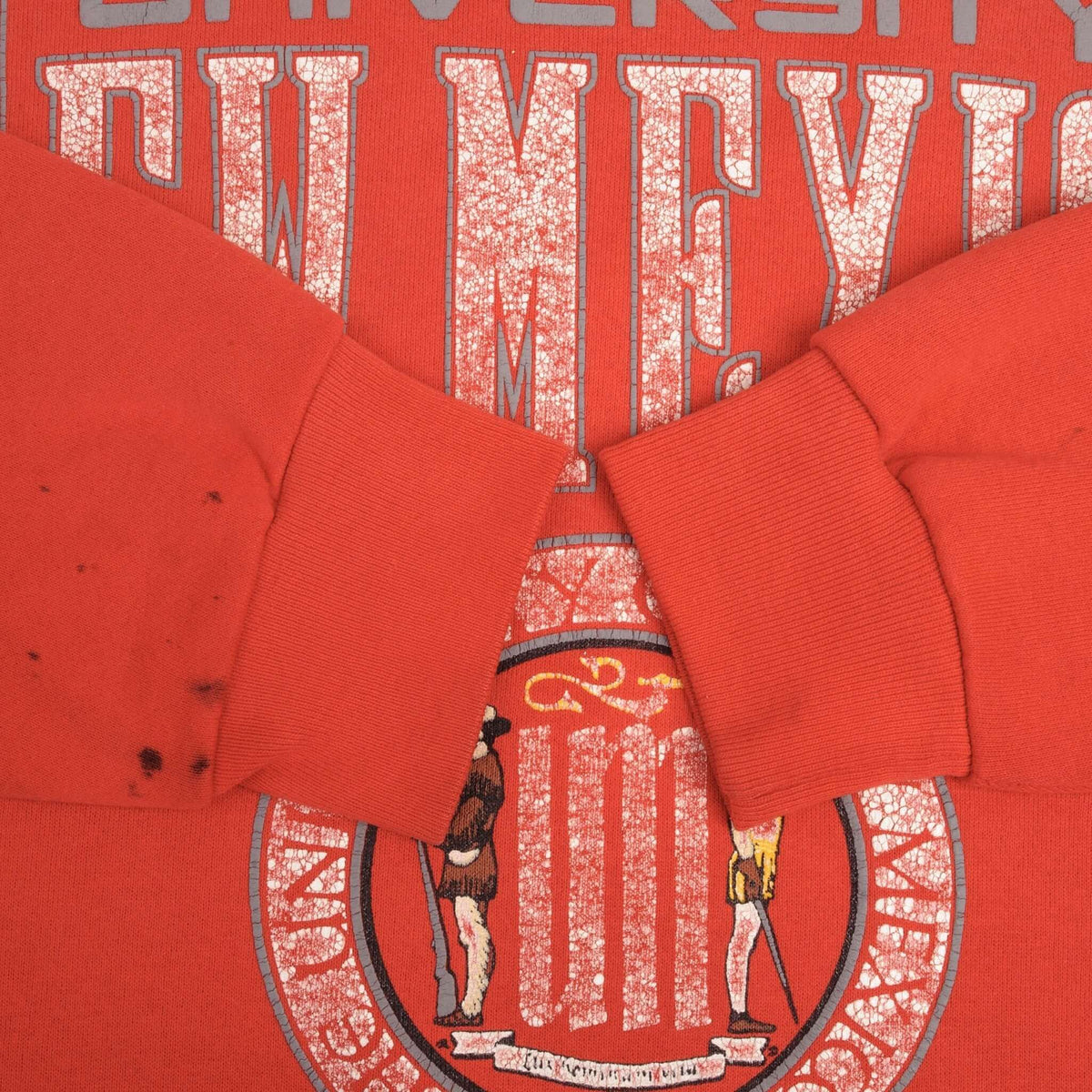 Close-up of ribbed cuffs and dark marks on red University of New Mexico sweatshirt
