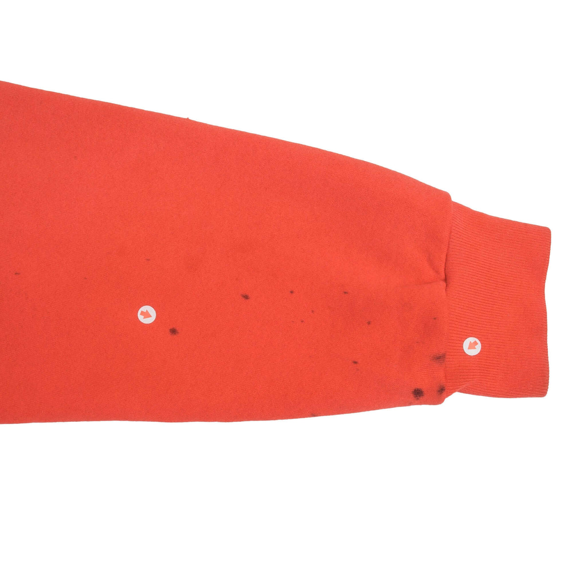Close-up of red sweatshirt sleeve and cuff with scattered dark marks