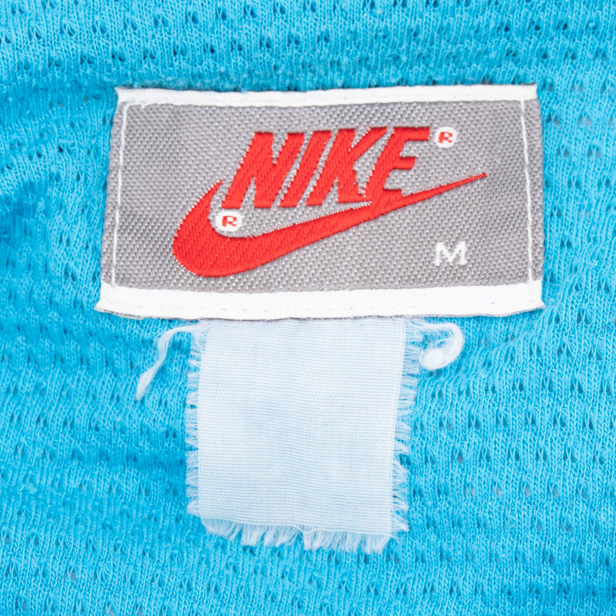 Nike neck label with red Swoosh and medium size marking on bright blue lining