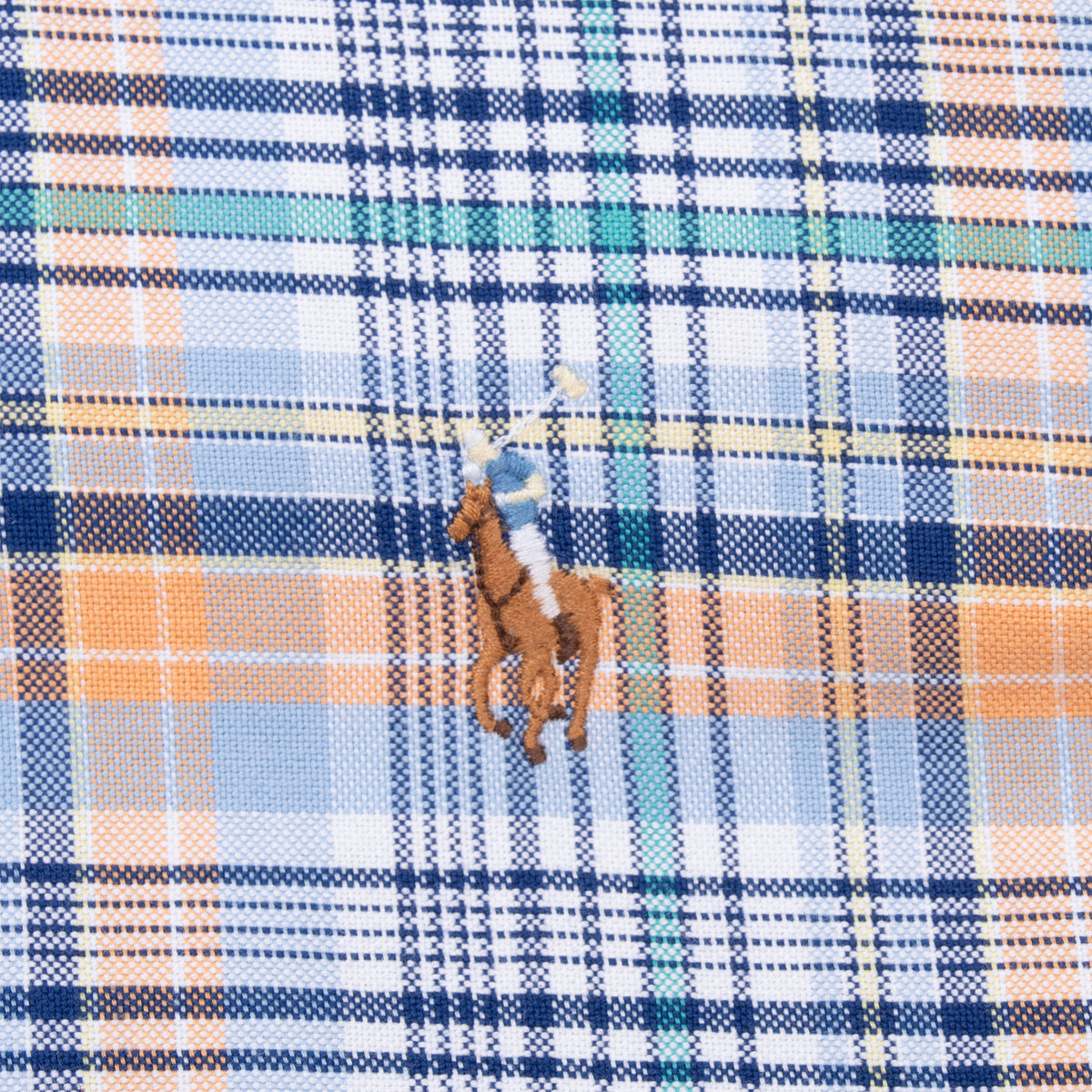 Close-up of embroidered Polo player chest logo on blue and orange plaid fabric
