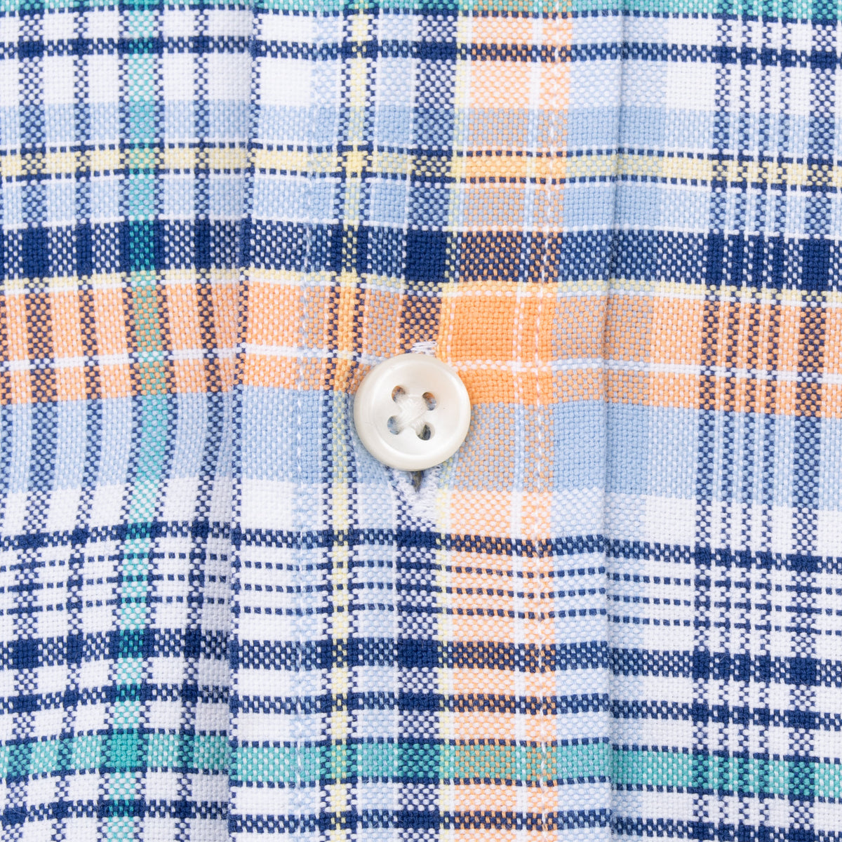 Close-up of white button and stitching on blue, white, orange and green plaid fabric
