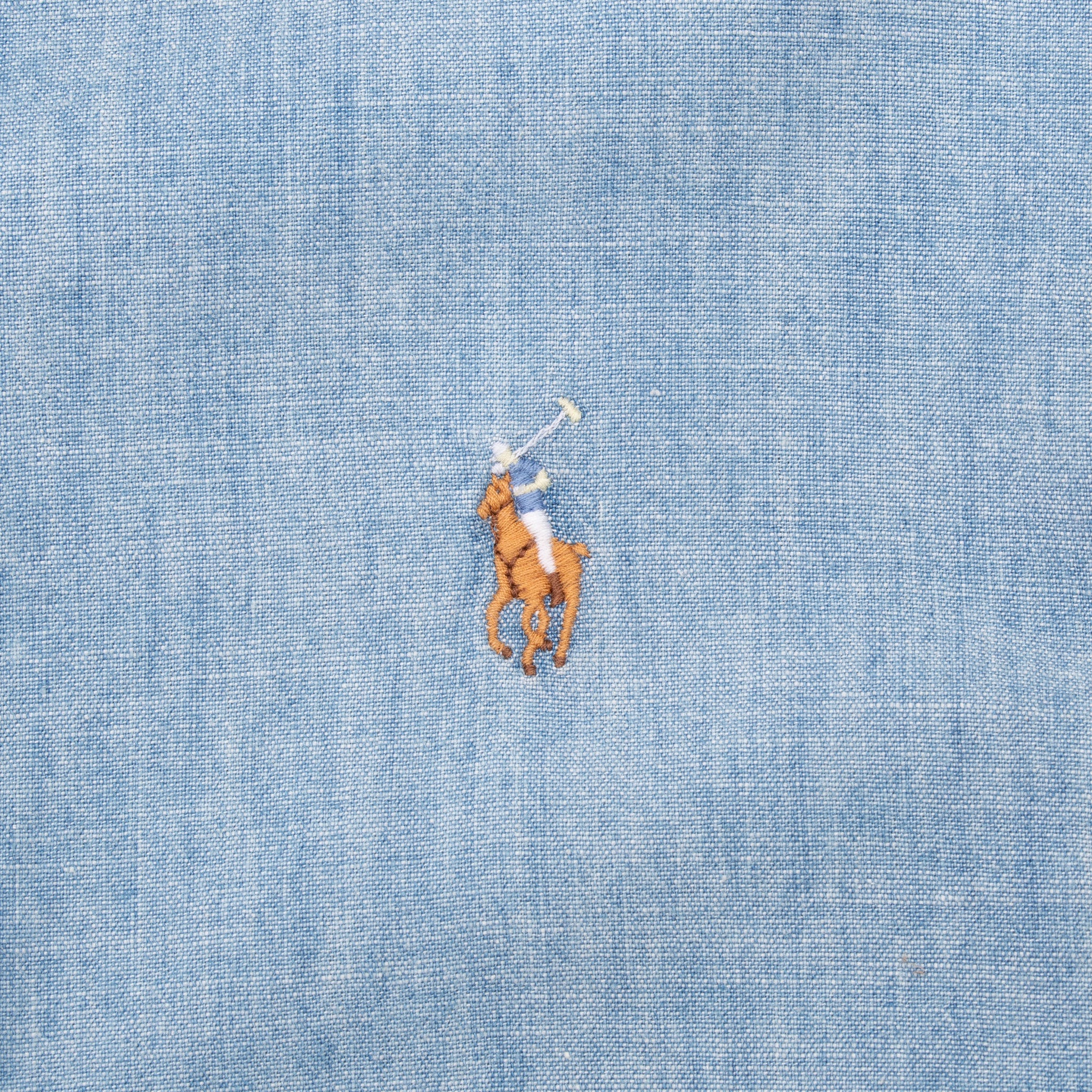 Close-up of multicolor Polo pony embroidery on blue chambray shirt chest