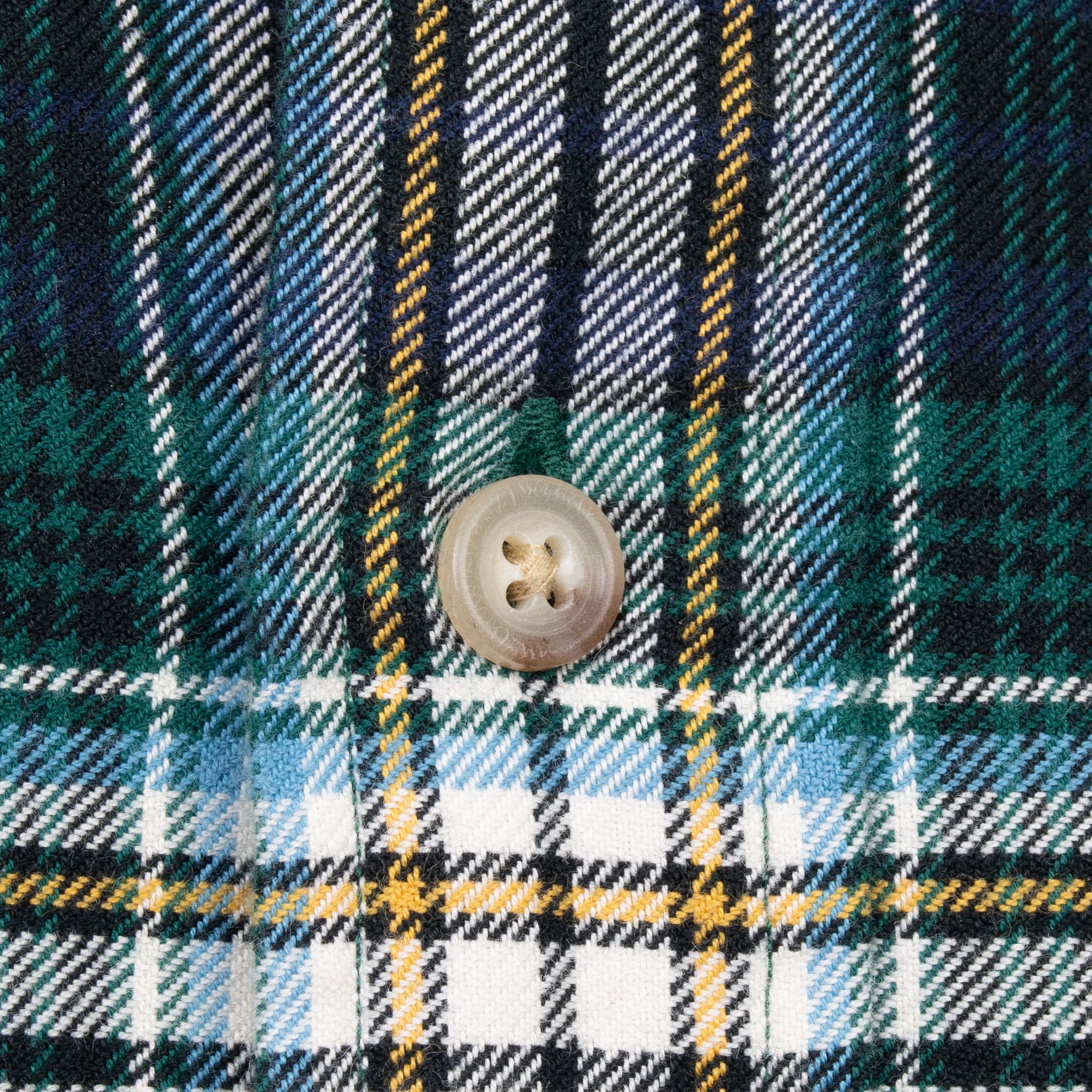 Close-up of button and green, navy, white, light blue and yellow plaid pattern