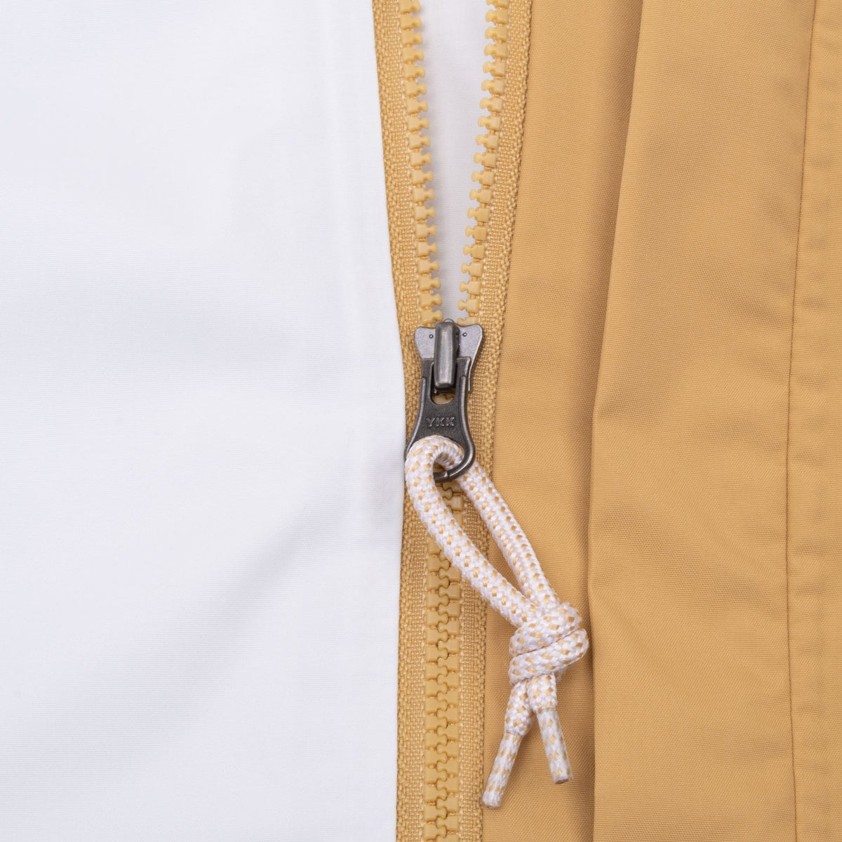 Close-up of tan front zipper with white and tan cord pull