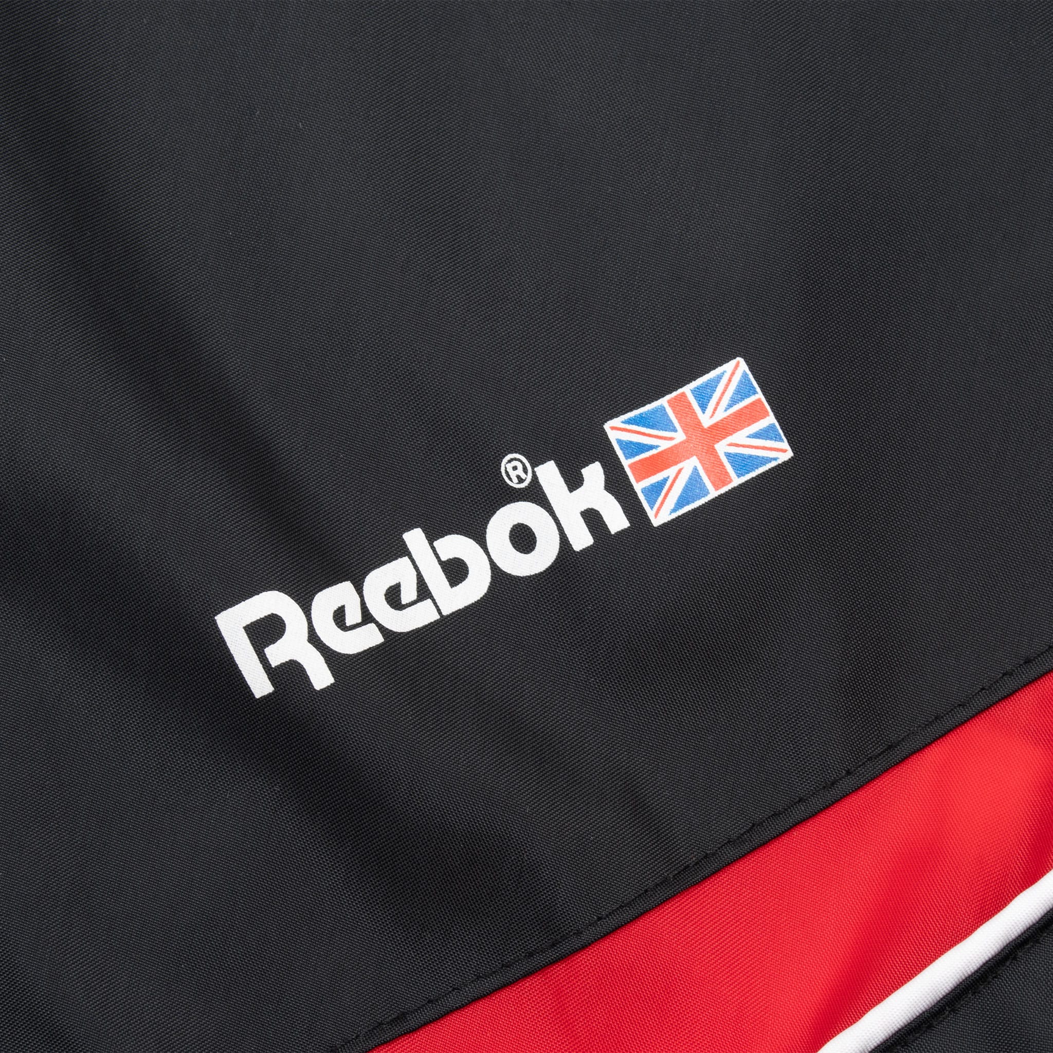 Close-up of white Reebok chest logo with Union Jack beside red stripe