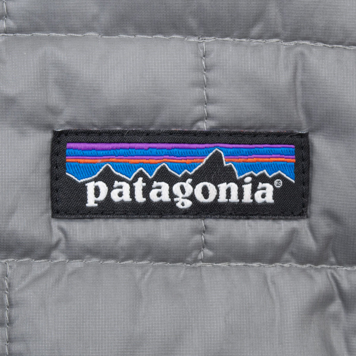 Close-up of Patagonia logo patch embroidered on grey quilted chest