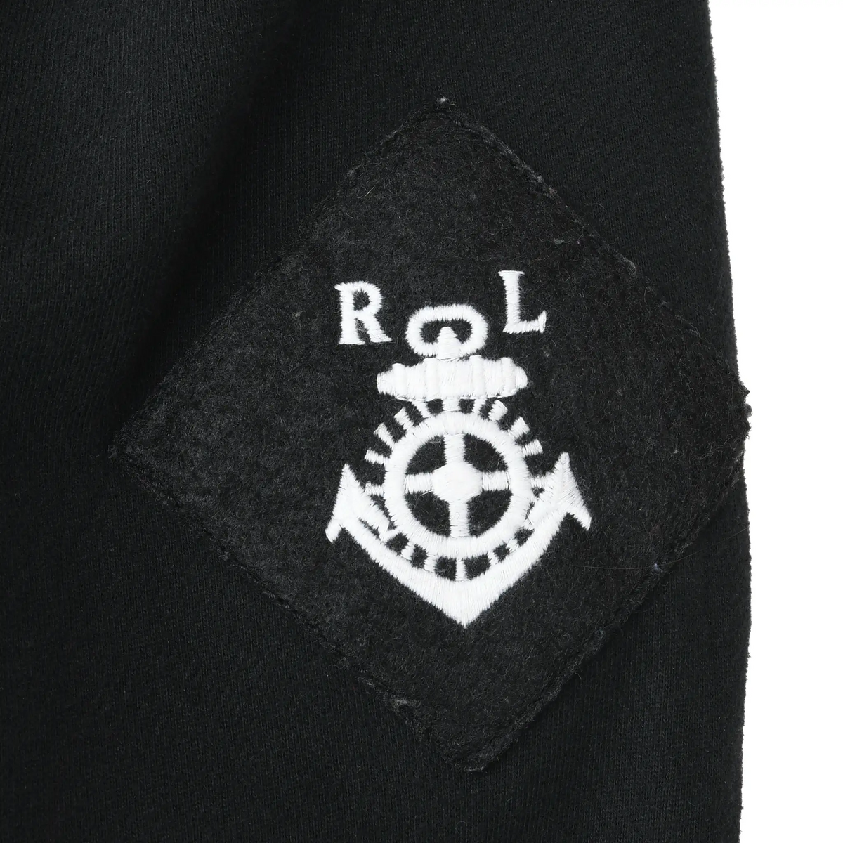 Close-up of white Polo Ralph Lauren crest embroidery on black sleeve patch
