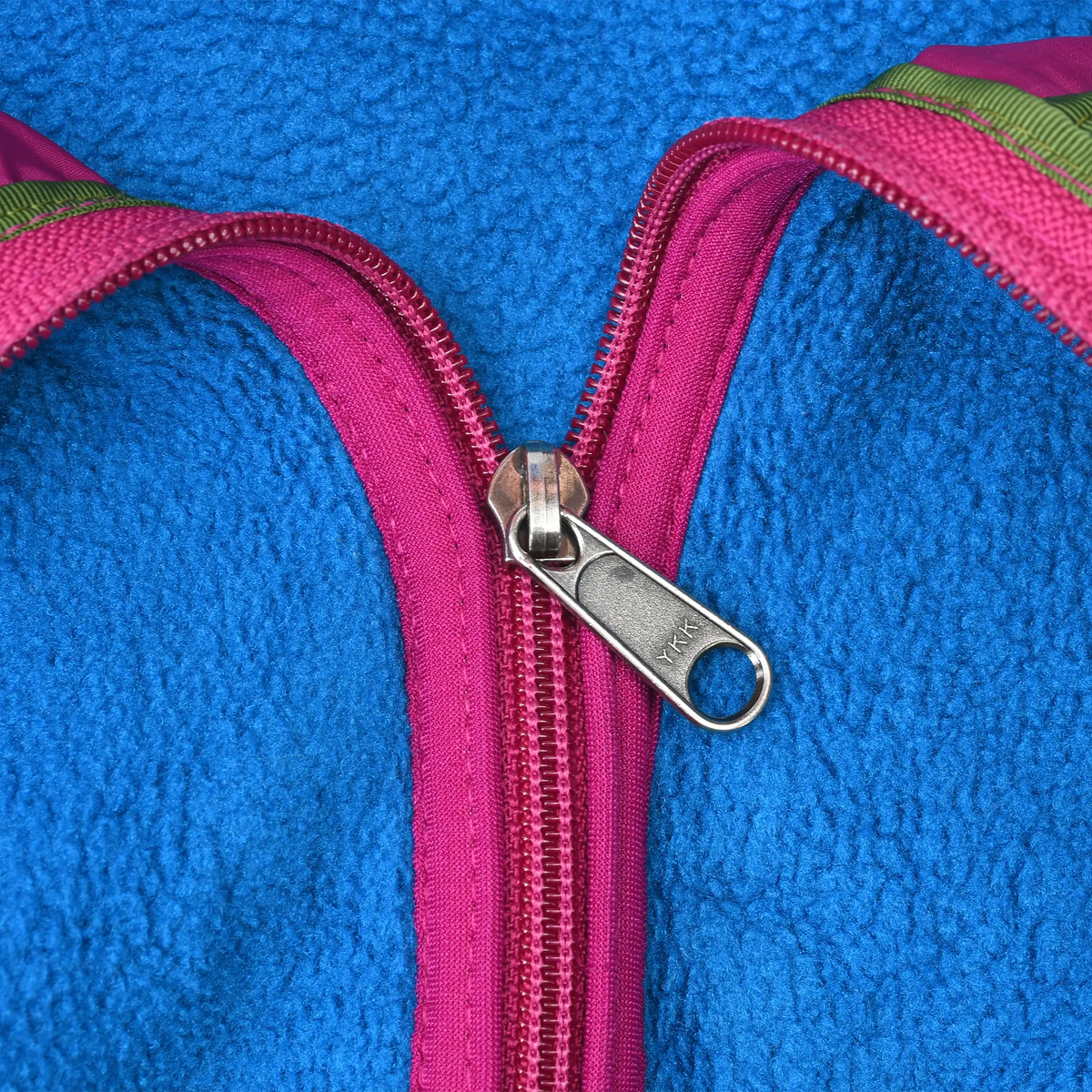 Close-up of metal zipper pull and magenta half-zip trim on blue fleece
