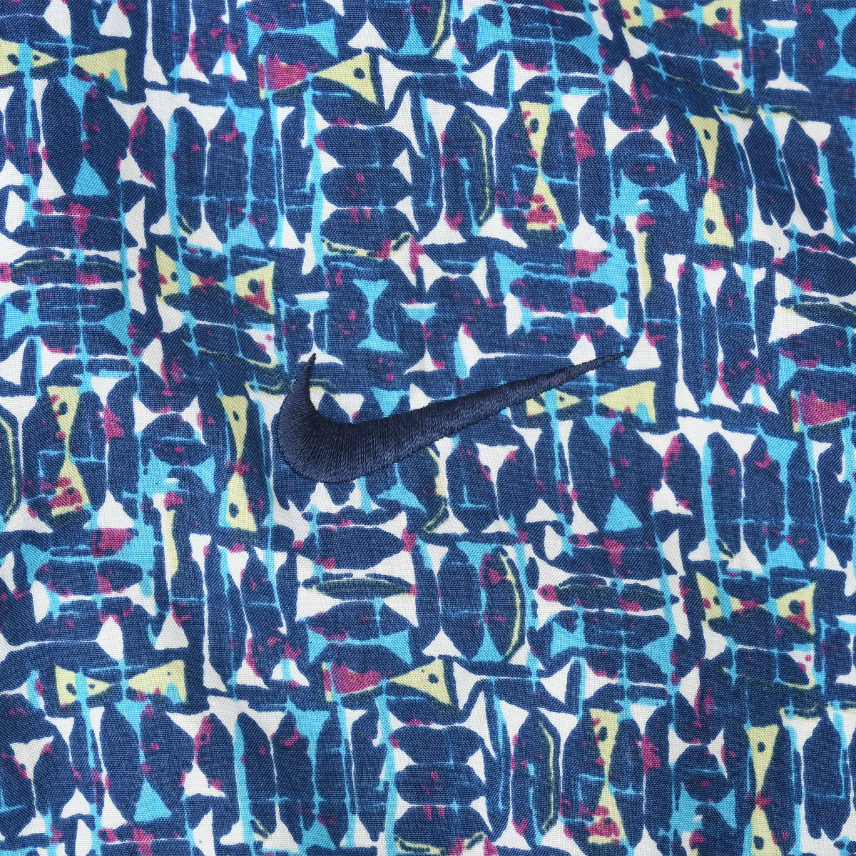 Close-up of navy Nike Swoosh embroidery on multicolor blue patterned fabric